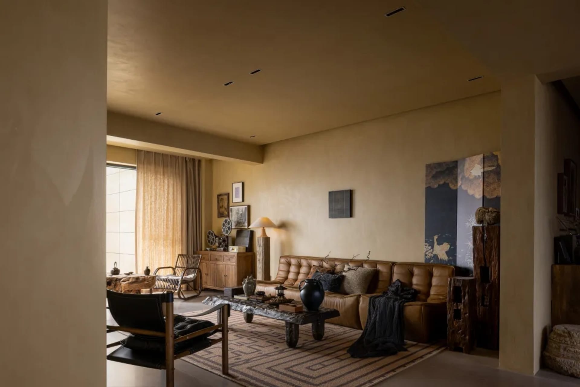 A modern living room with a leather sofa, industrial lighting, and art on the walls.
