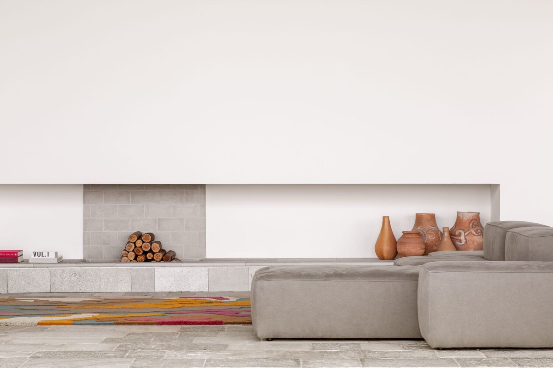 A minimalist living room featuring concrete furniture and soft textiles.