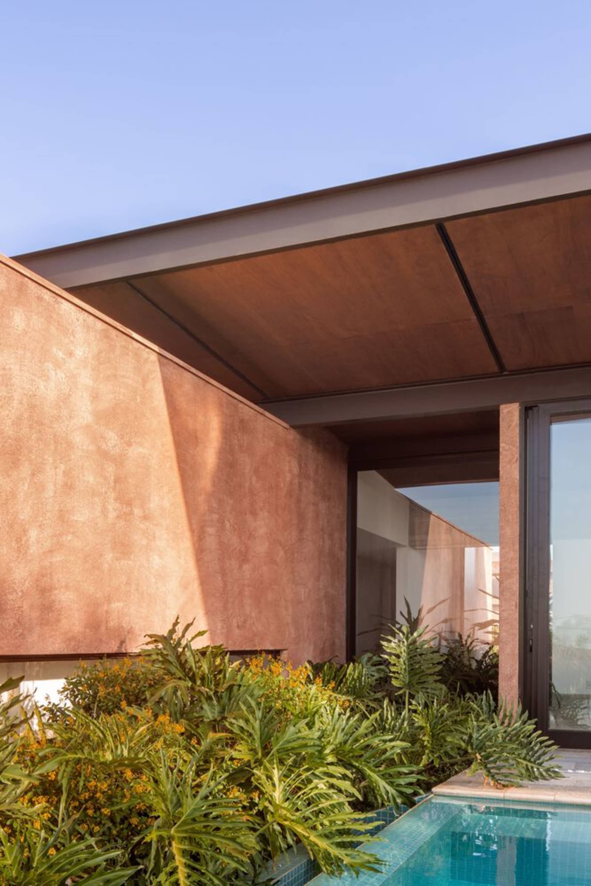 Modern residential exterior featuring a minimalist design with concrete walls and a glass roof.