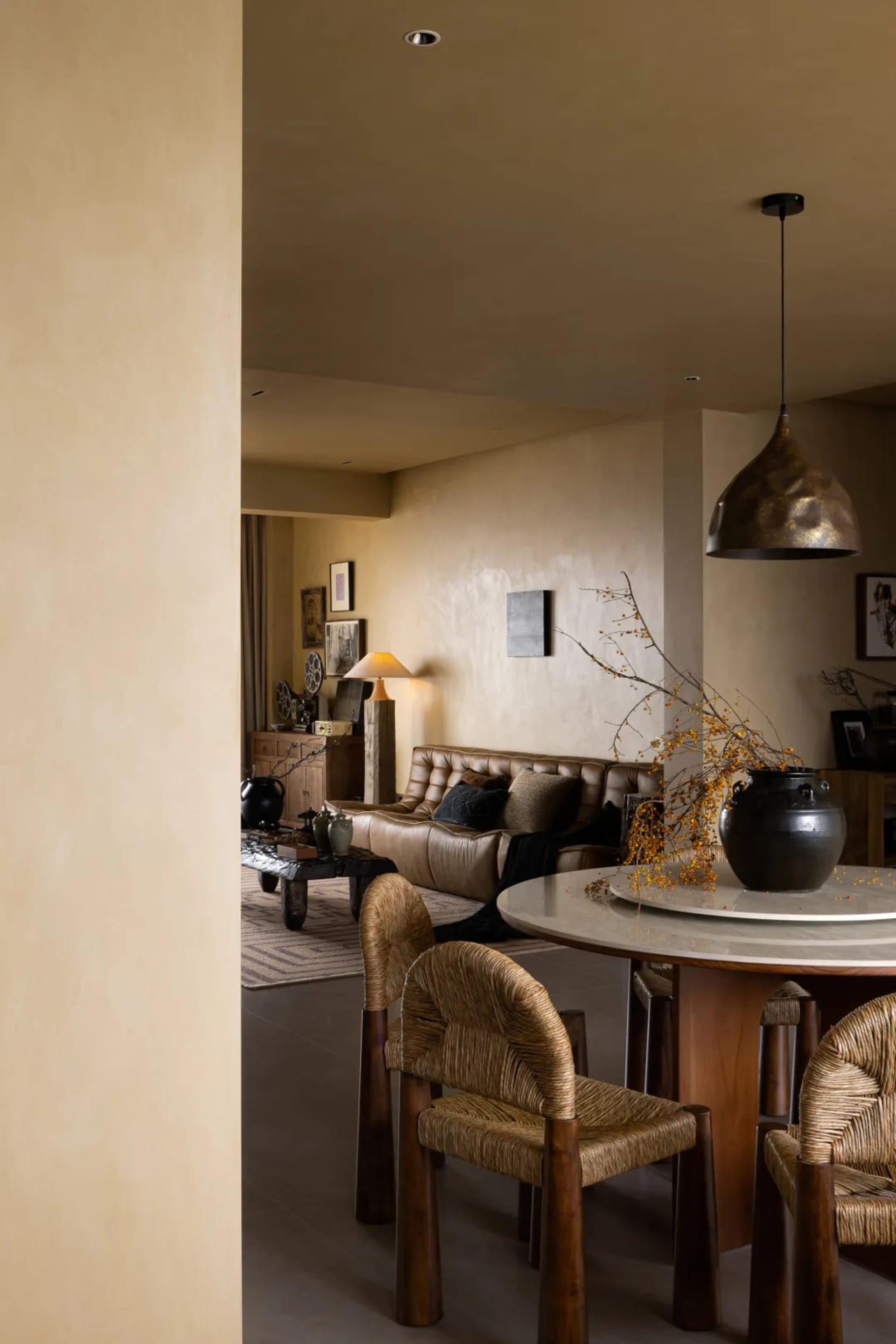 Modern living room featuring a marble table, leather sofa, and woven chairs.