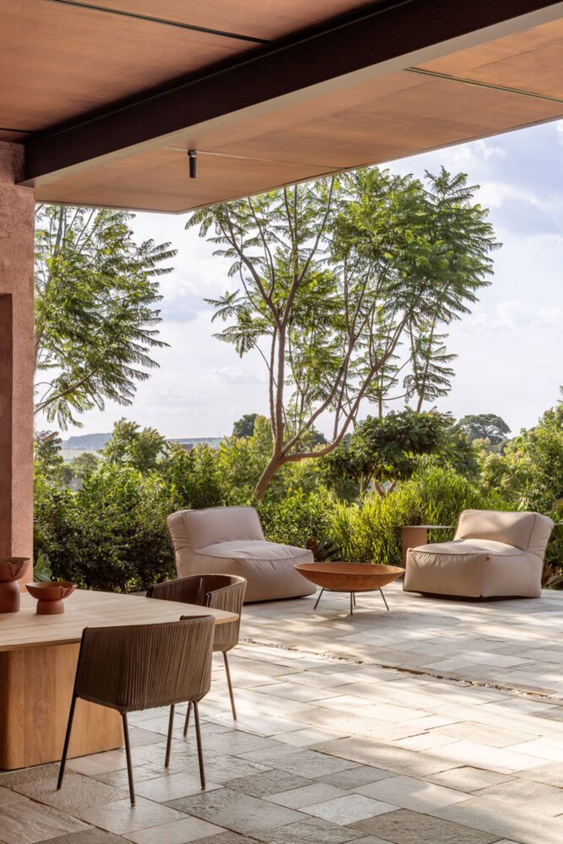 Modern outdoor living space featuring comfortable cushions and a fire pit surrounded by greenery.