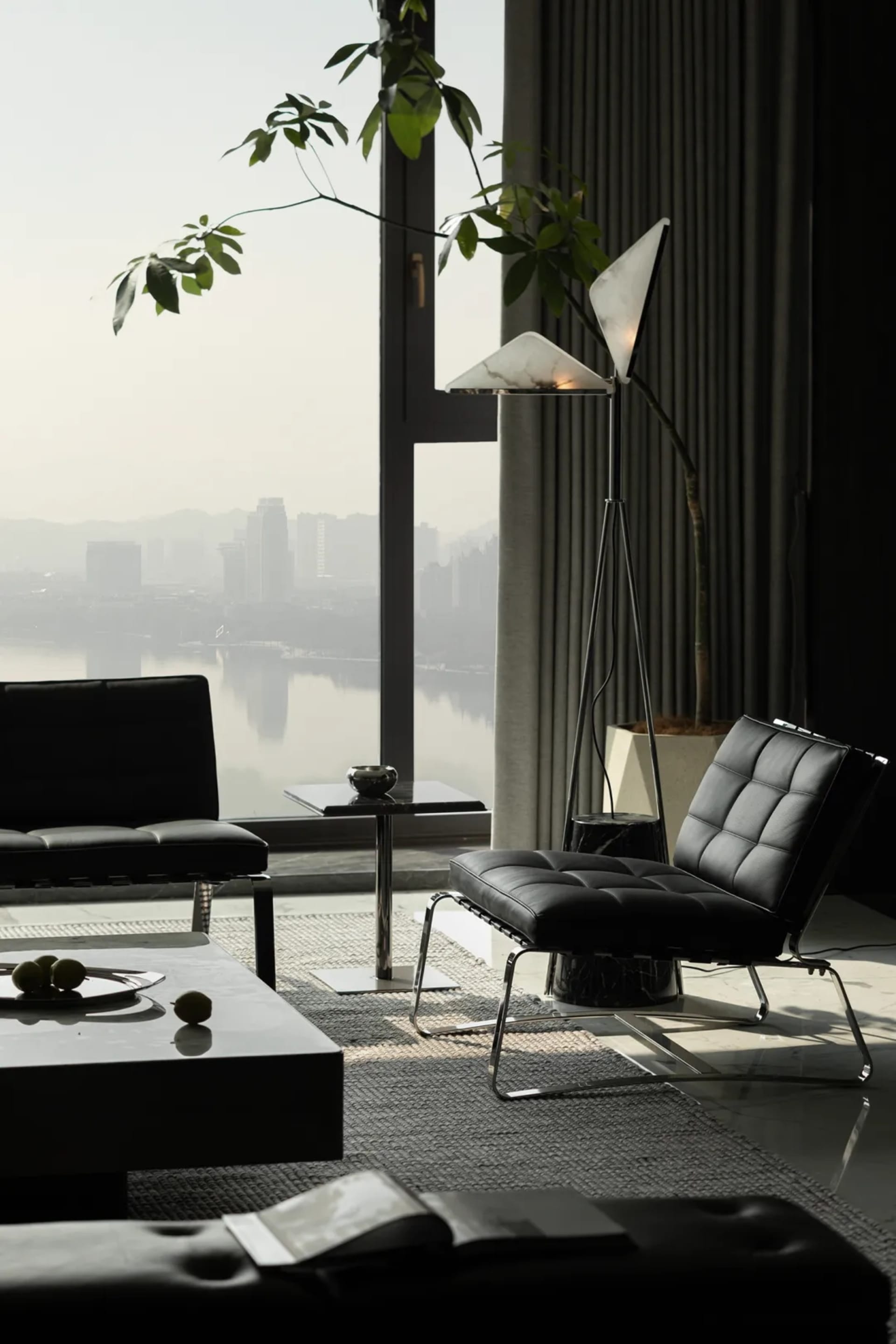 A sleek, minimalist living room featuring leather furniture, marble accents, and a glass coffee table.