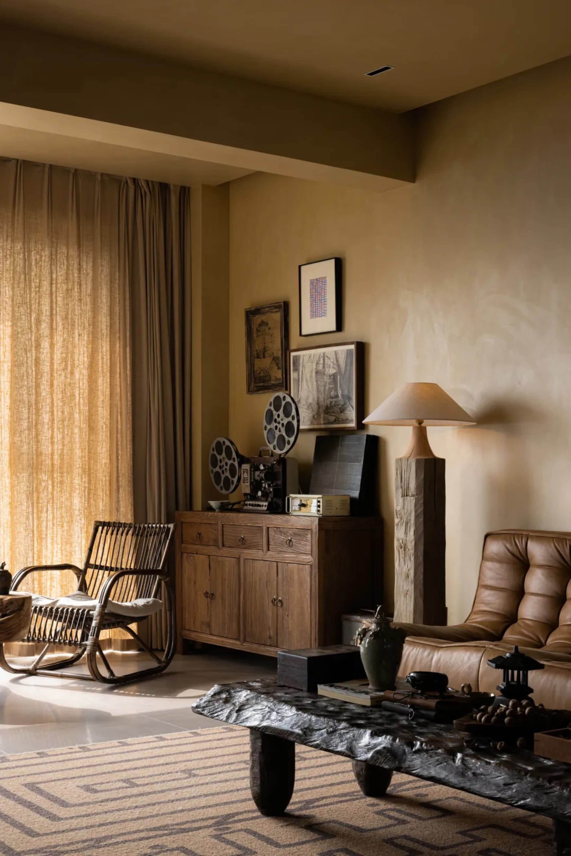 A modern living room with wooden furniture, canvas curtains, ceramic vases, brick walls, and rattan accents.