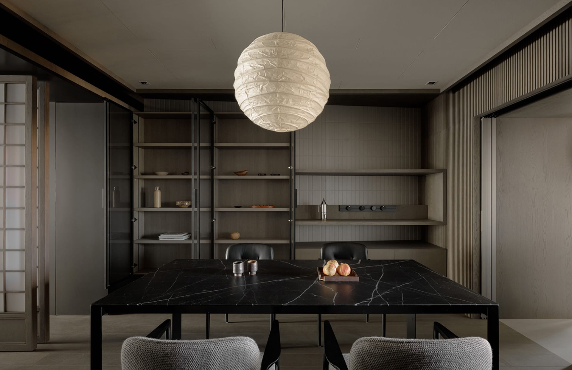 A minimalist dining room featuring a black marble table and fabric upholstered chairs.