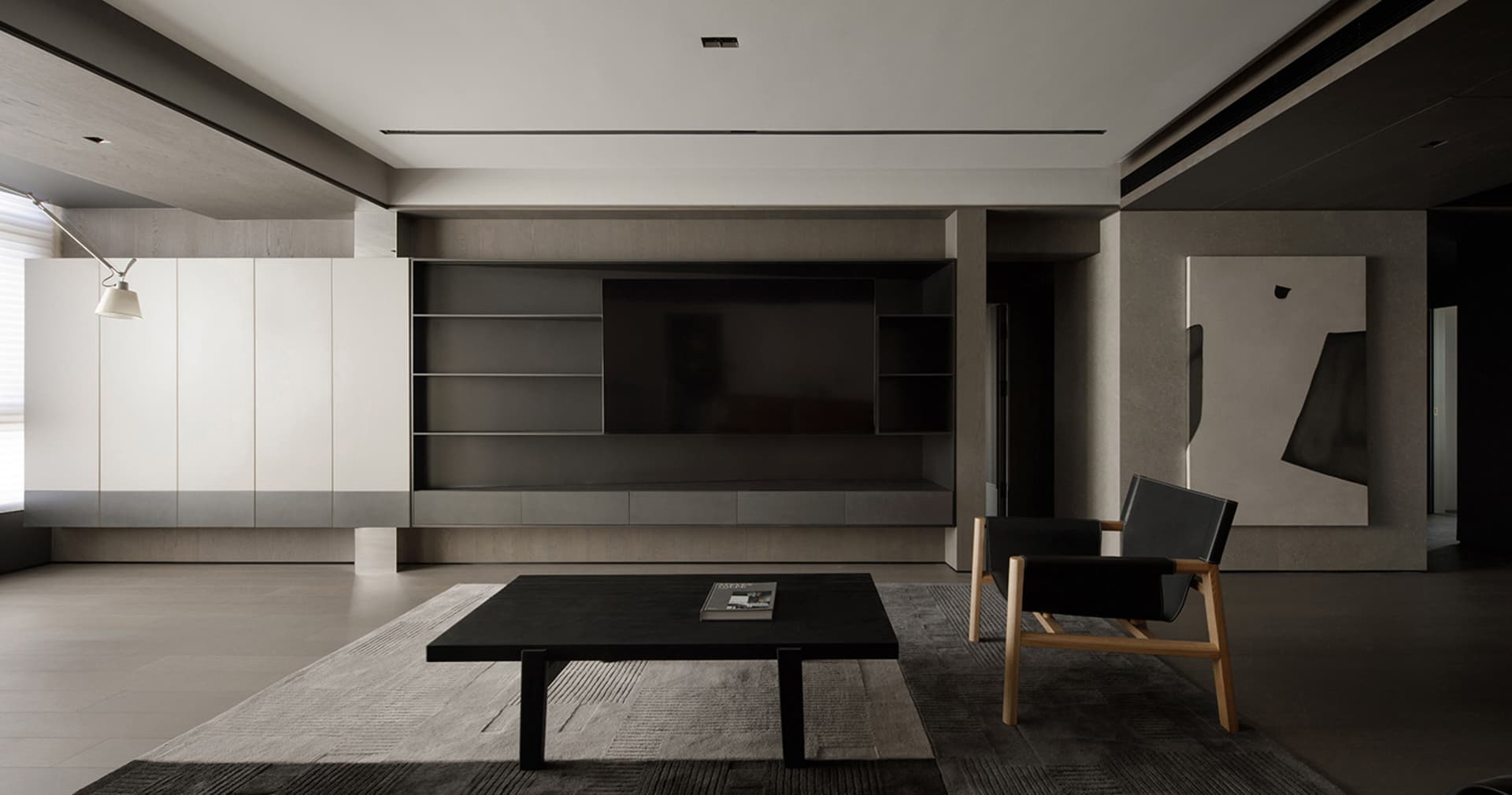 A modern, minimalist living room featuring concrete walls and black furniture.