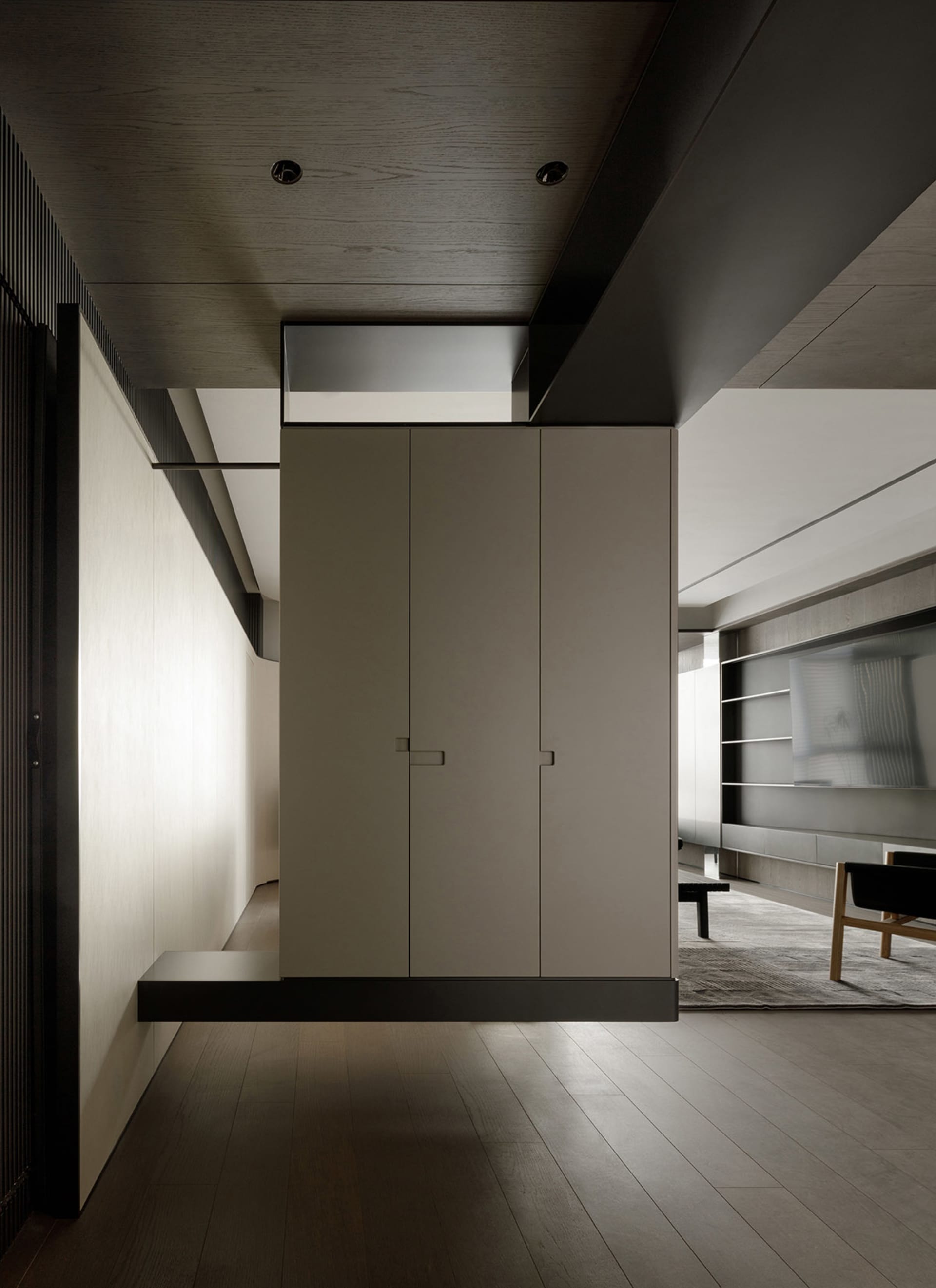 Modern apartment interior with dark wood paneling and white cabinet doors.