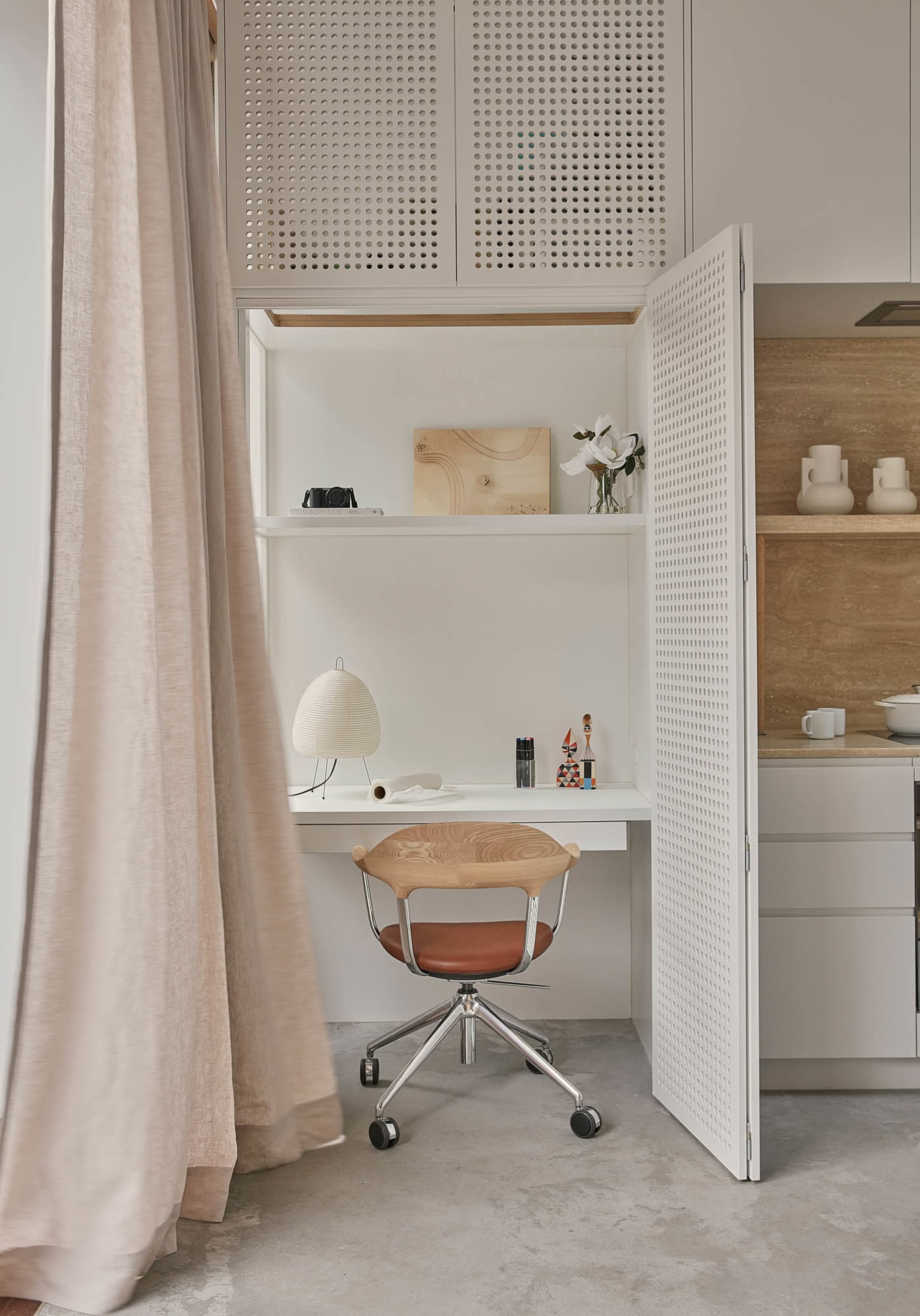 A minimalist home office with a desk, chair, and decorative items.