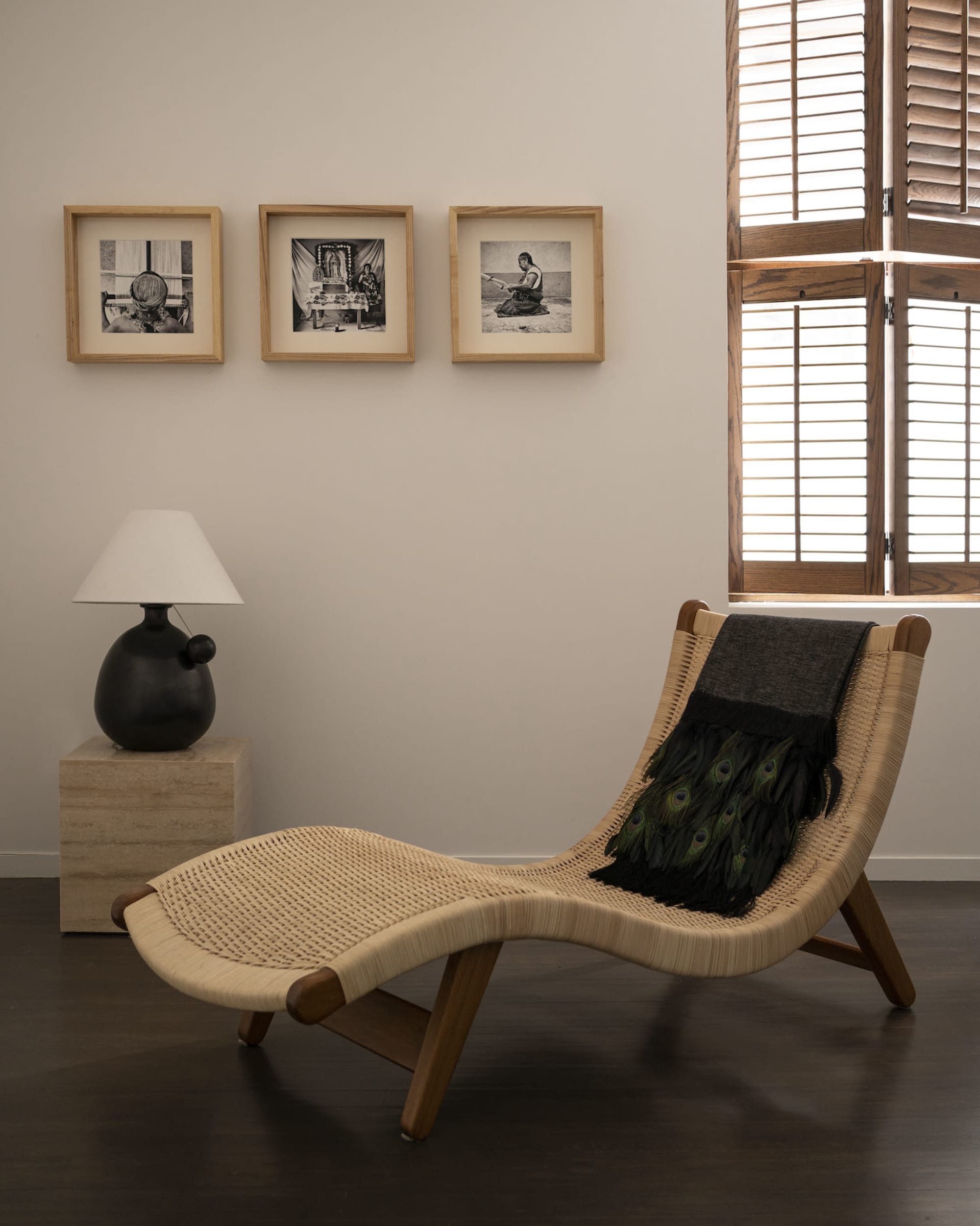 Modern living room with a wooden framed lounge chair and framed photographs on the wall.