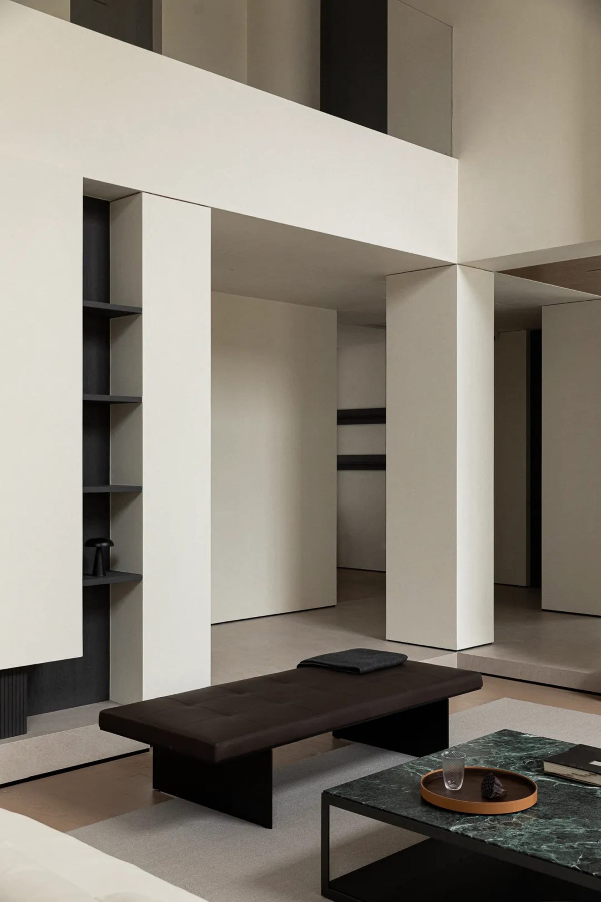 Modern living room featuring a black leather ottoman, marble coffee table, and stone and steel elements.
