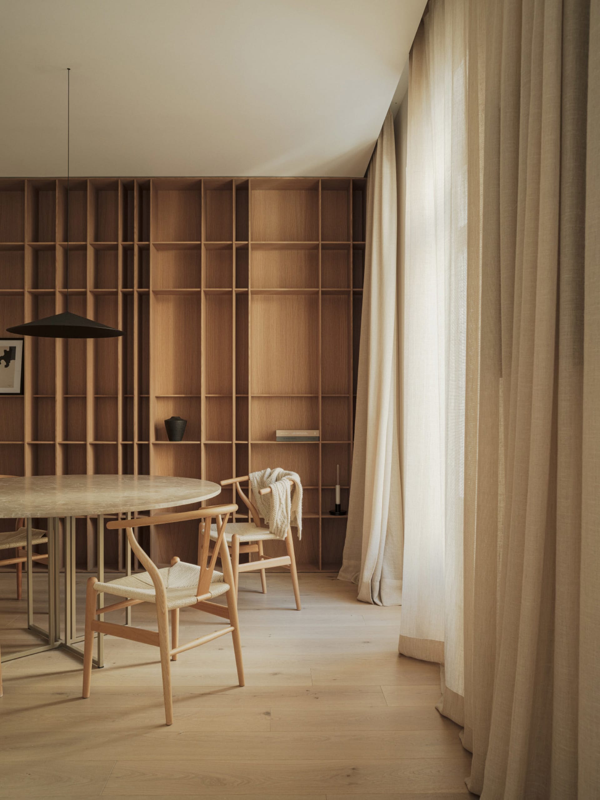 A modern minimalist library interior with wooden shelves and a round table.