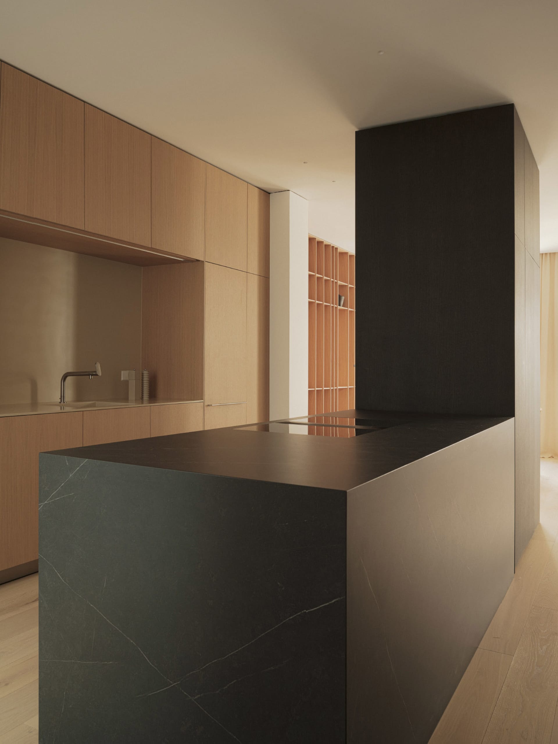 A modern minimalist kitchen with black stone island and wooden panels