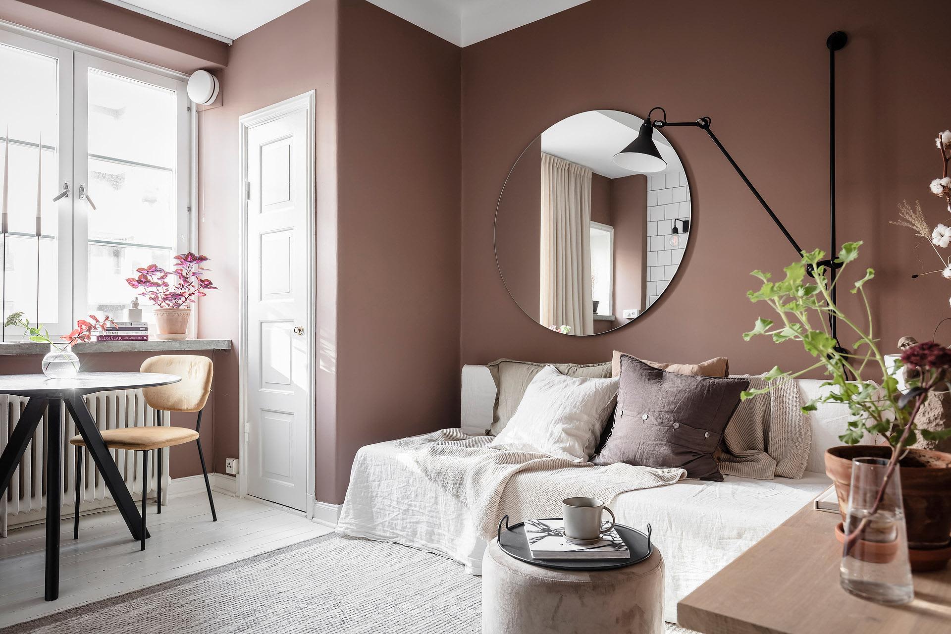 A minimalist living room with wooden flooring, fabric cushions, and metal accents.