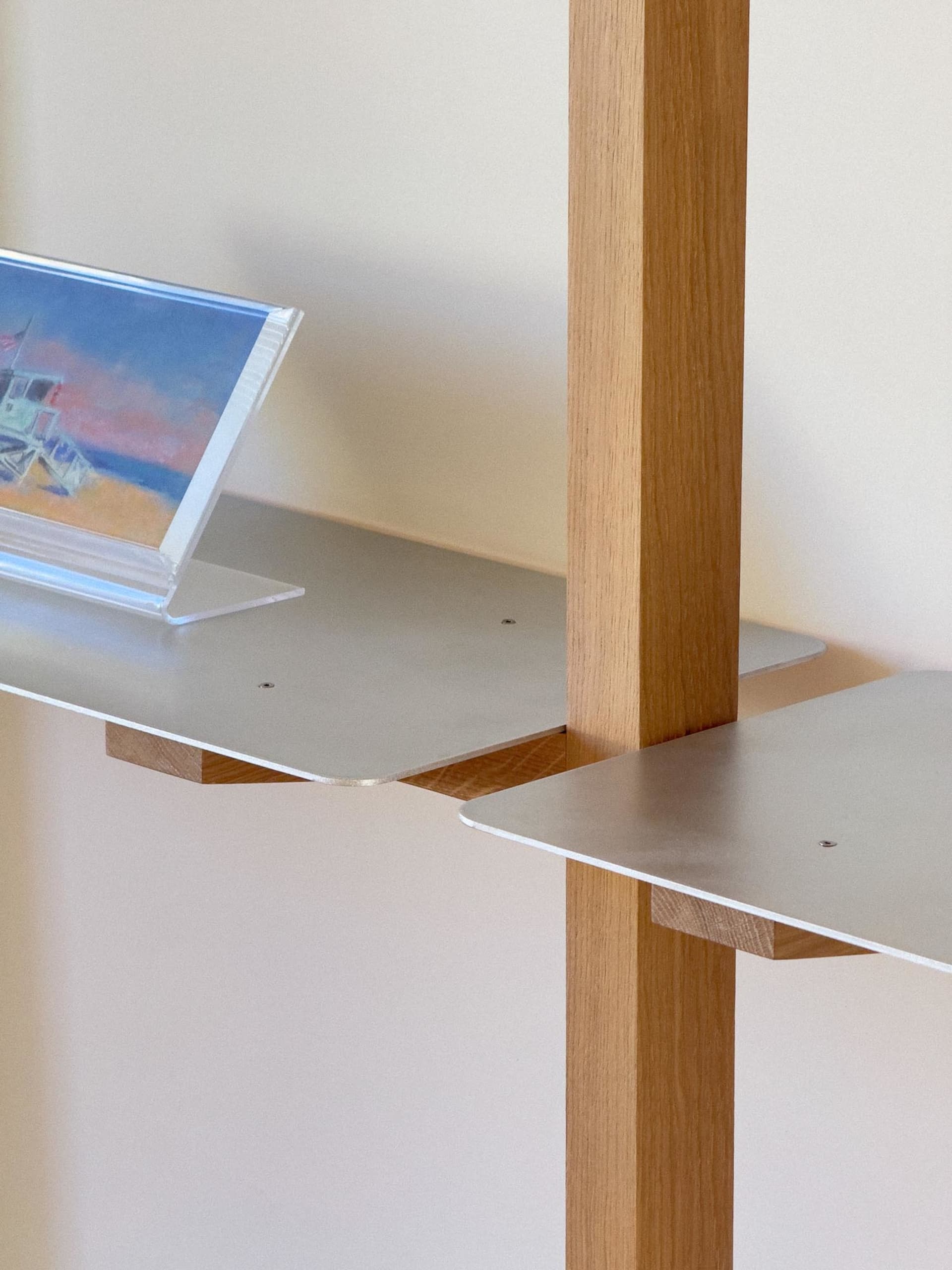 A modern metal desk with a clear acrylic frame holds a framed picture of a beach scene.