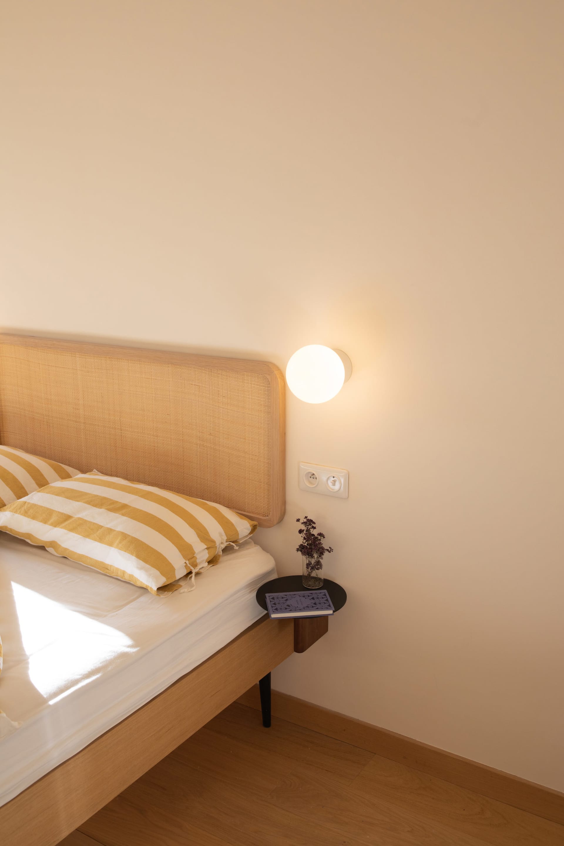 A minimalist bedroom with a wooden bed and yellow-striped pillows.