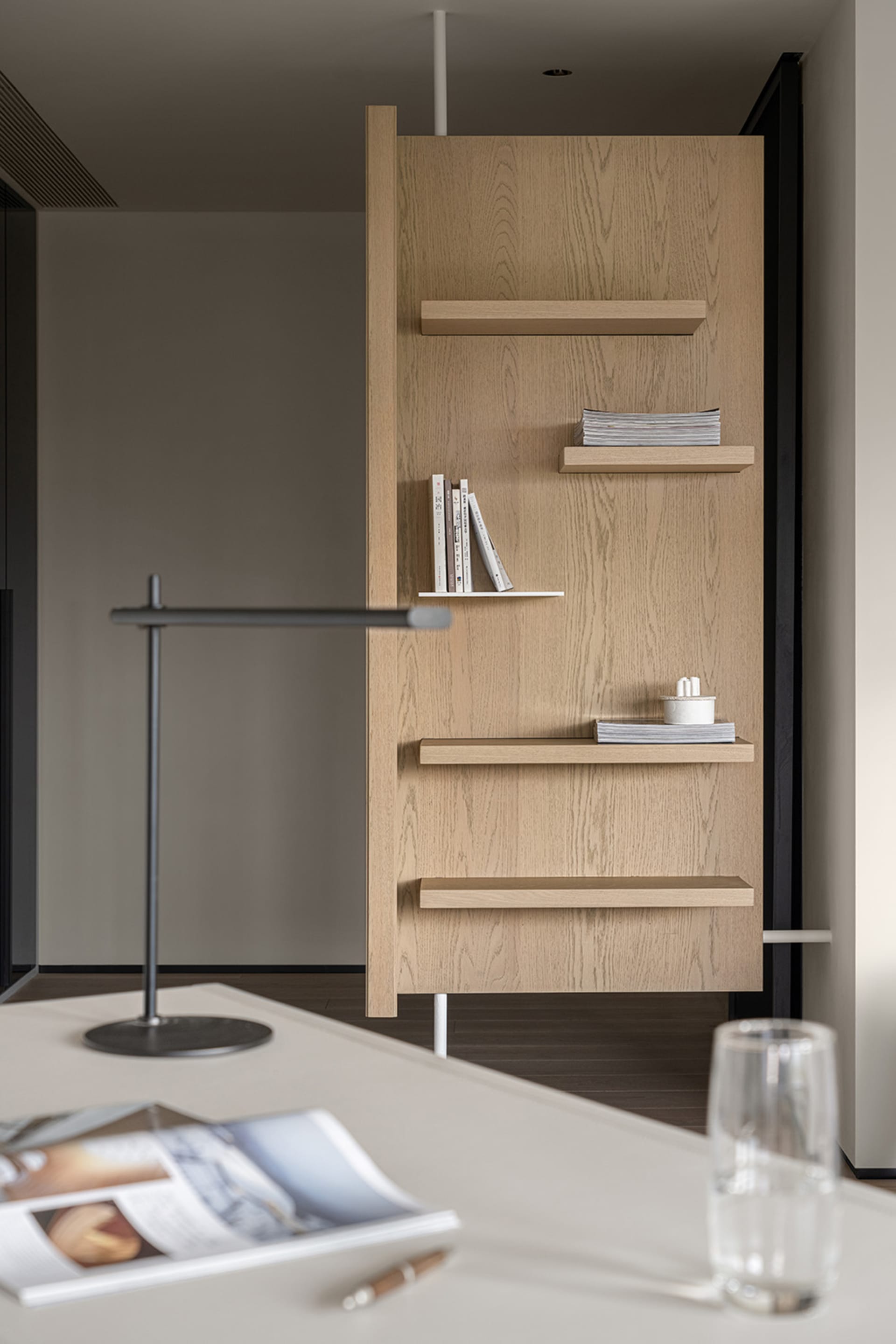 A modern office space featuring wooden shelves with books and a lamp.