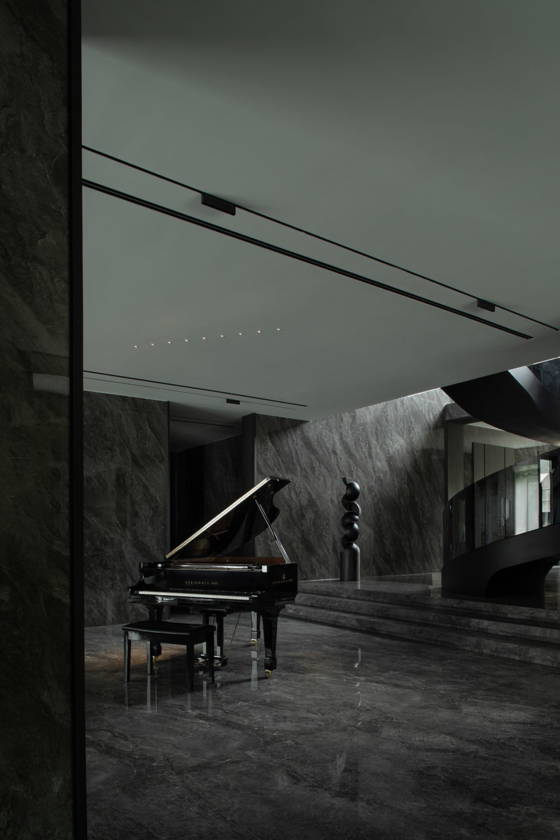 A sleek, minimalist piano room with black marble floors and walls, featuring a black grand piano with a black metal column in