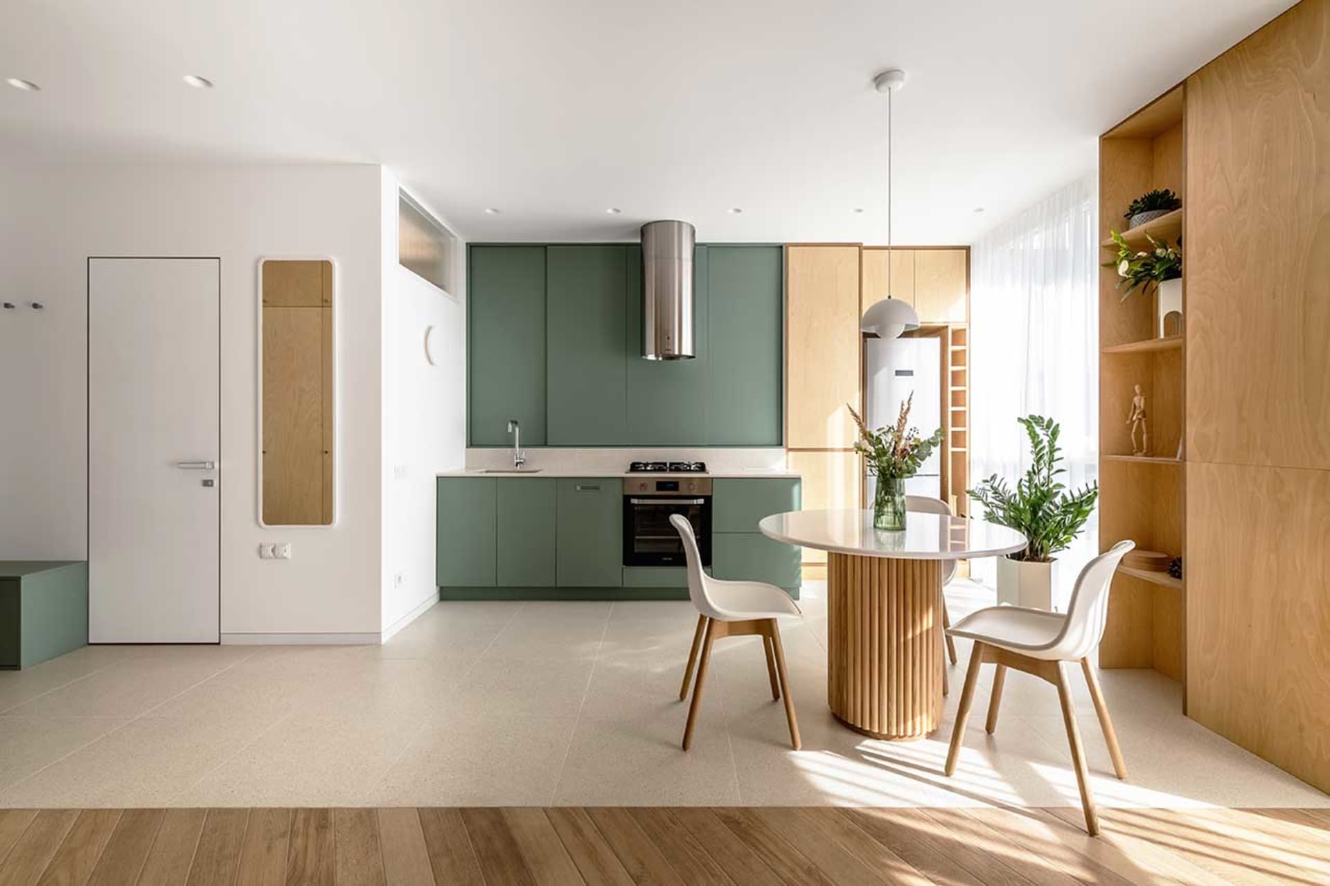 A modern kitchen with green cabinets and wooden accents.