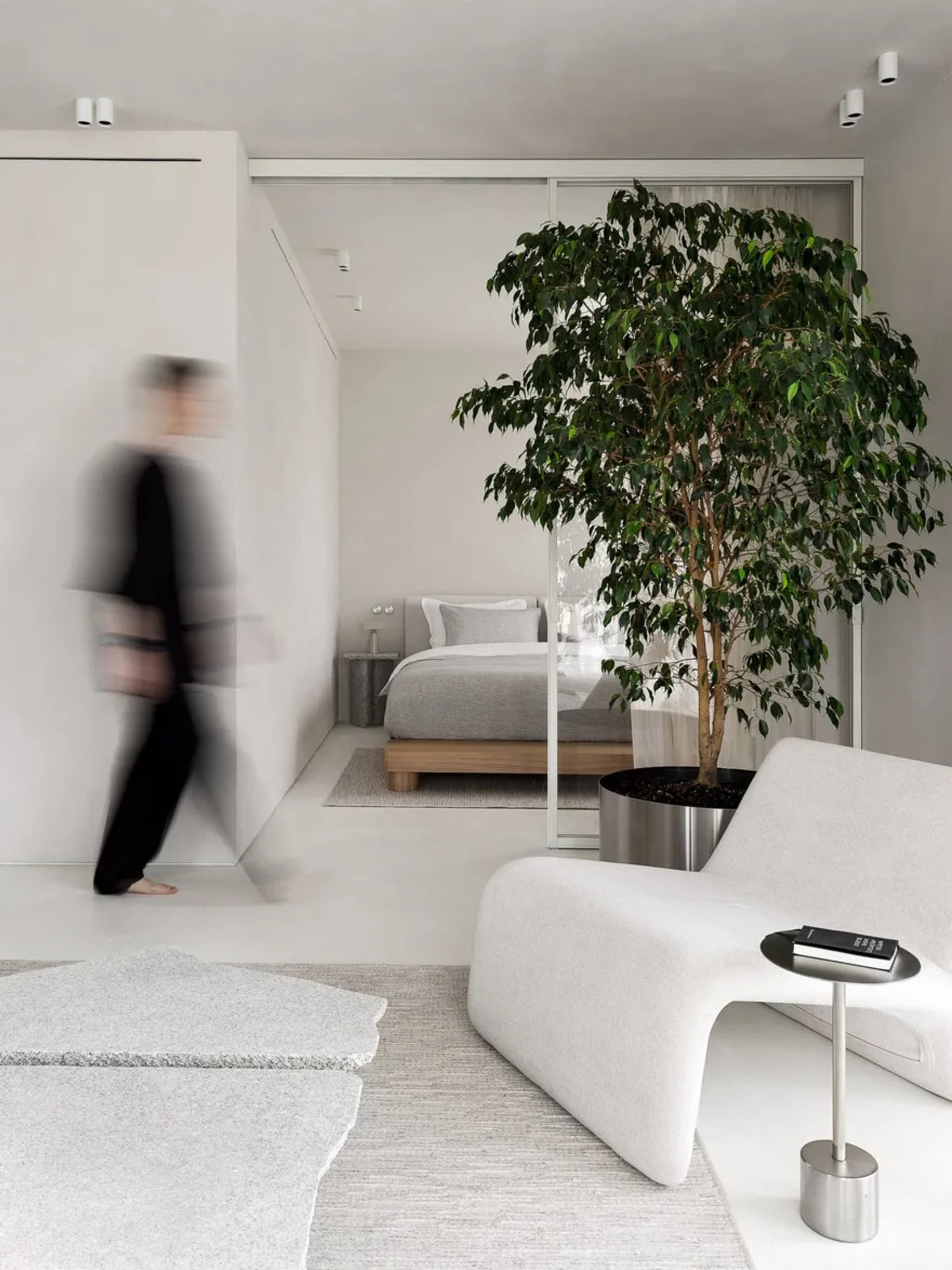 A modern living room featuring fabric furniture, glass planters, and metal accents.