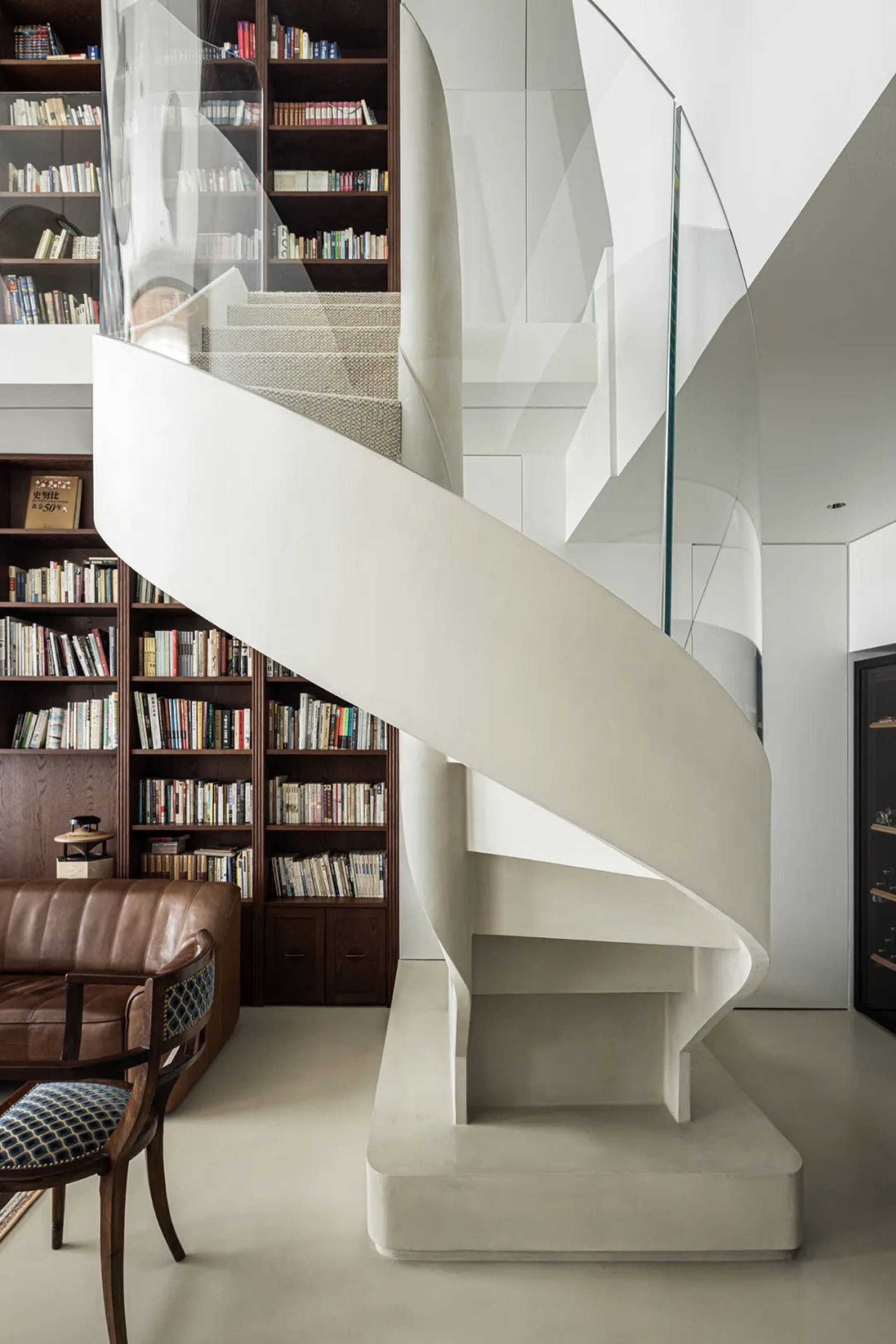 A modern white staircase with a glass railing in a library setting.