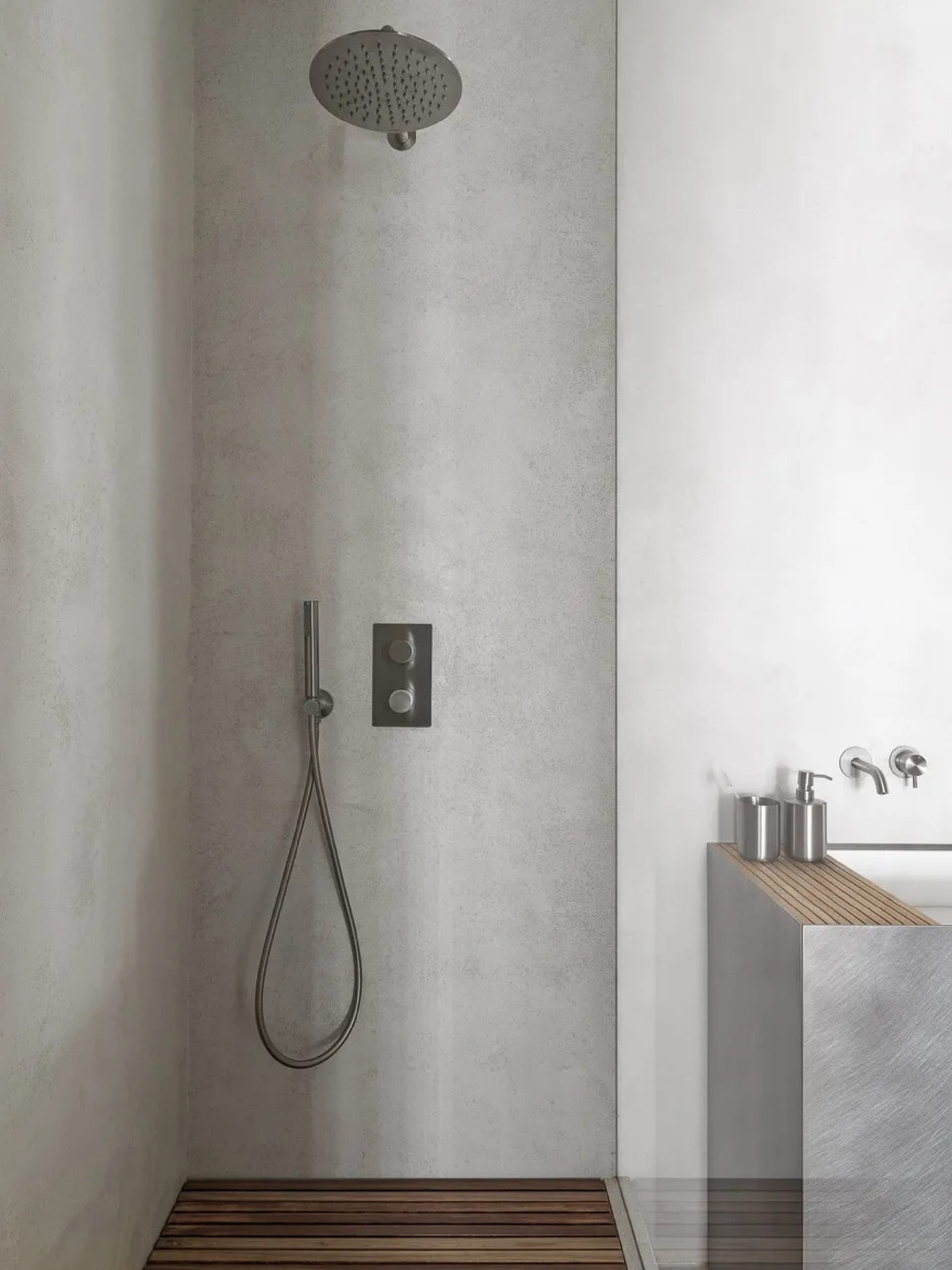 A minimalist bathroom with concrete walls and a wooden floor.