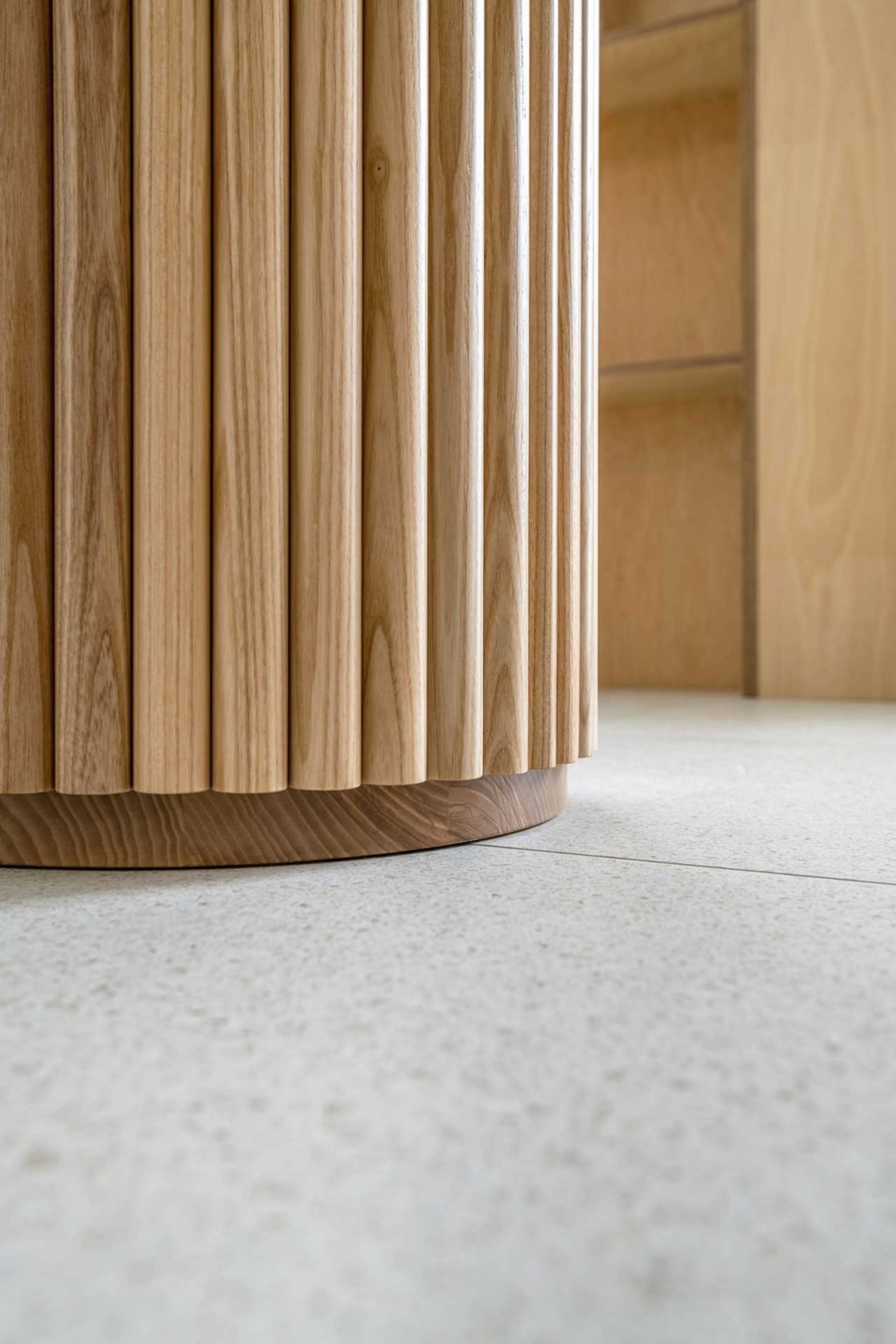 Close-up of a modern furniture piece with fluted wooden legs and a sleek, minimalist design.