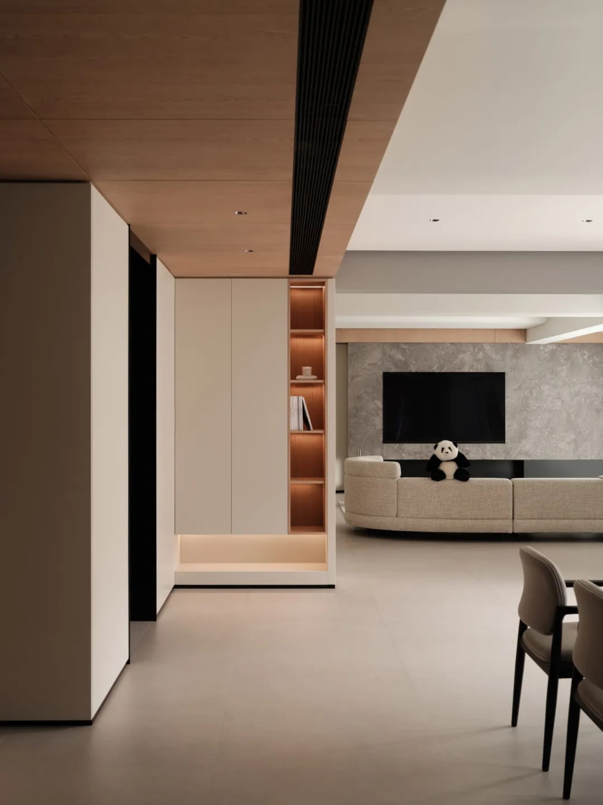 A modern living room featuring a composite wood, marble, and leather interior with a large television and plush seating.