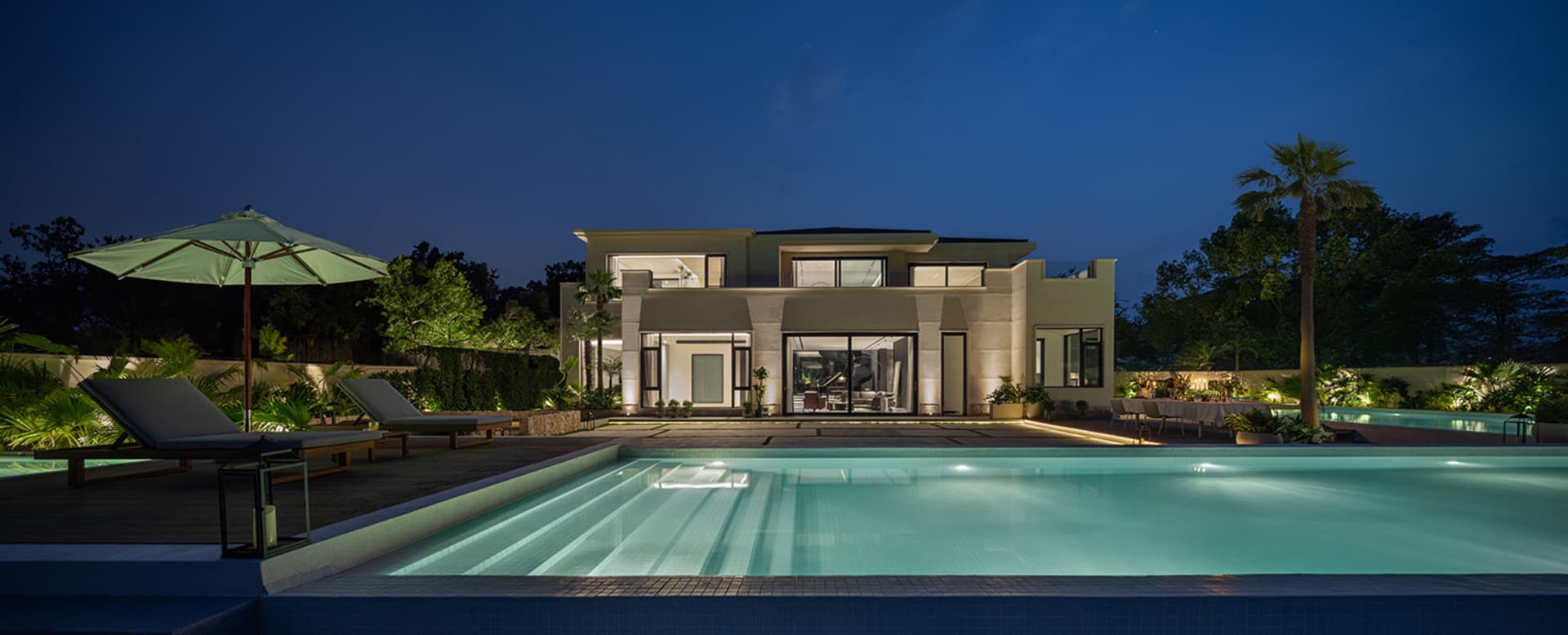 A modern residential exterior illuminated with concrete and glass features.