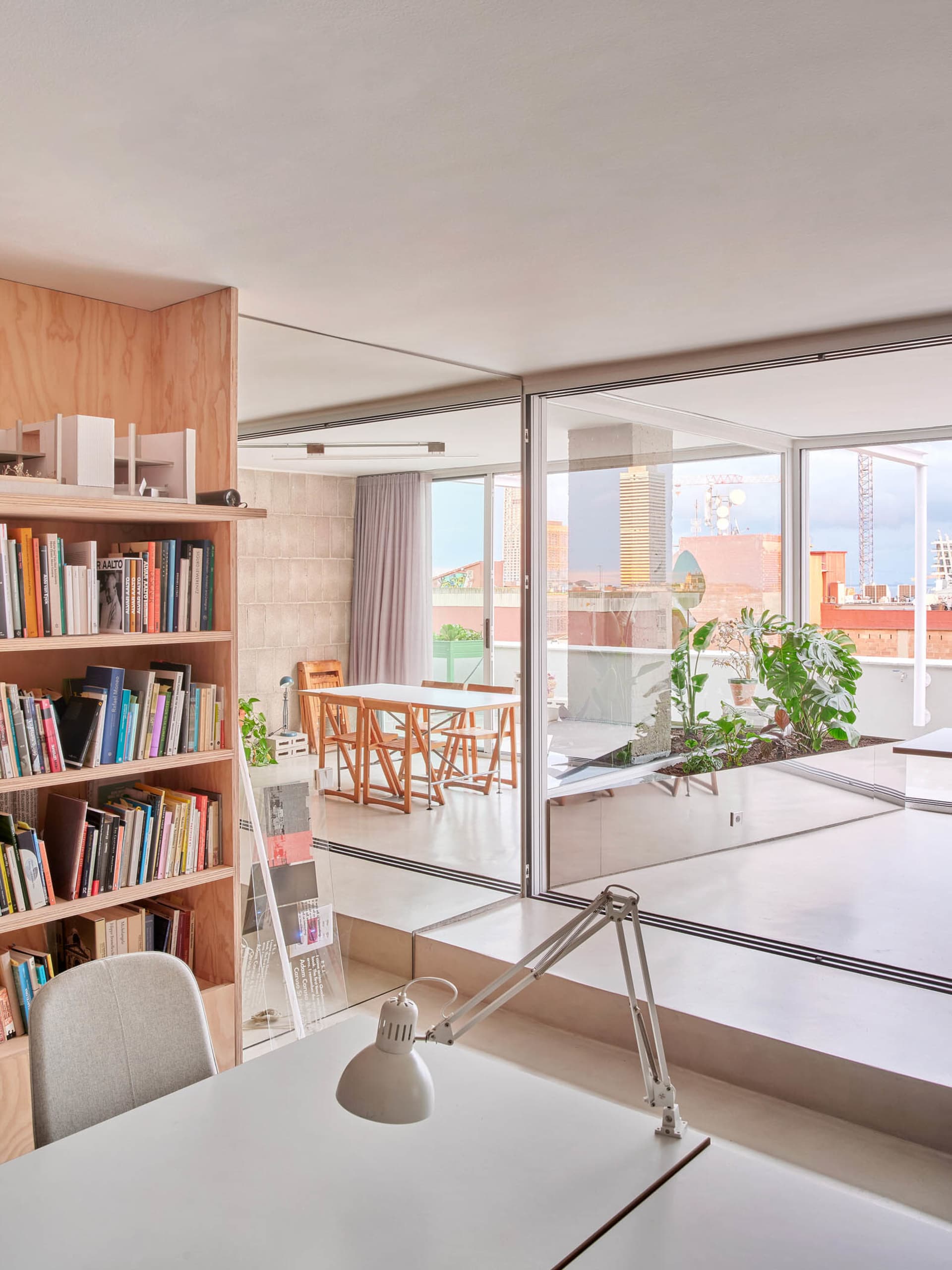 Minimalist living room with concrete walls, a white desk, and a bookshelf