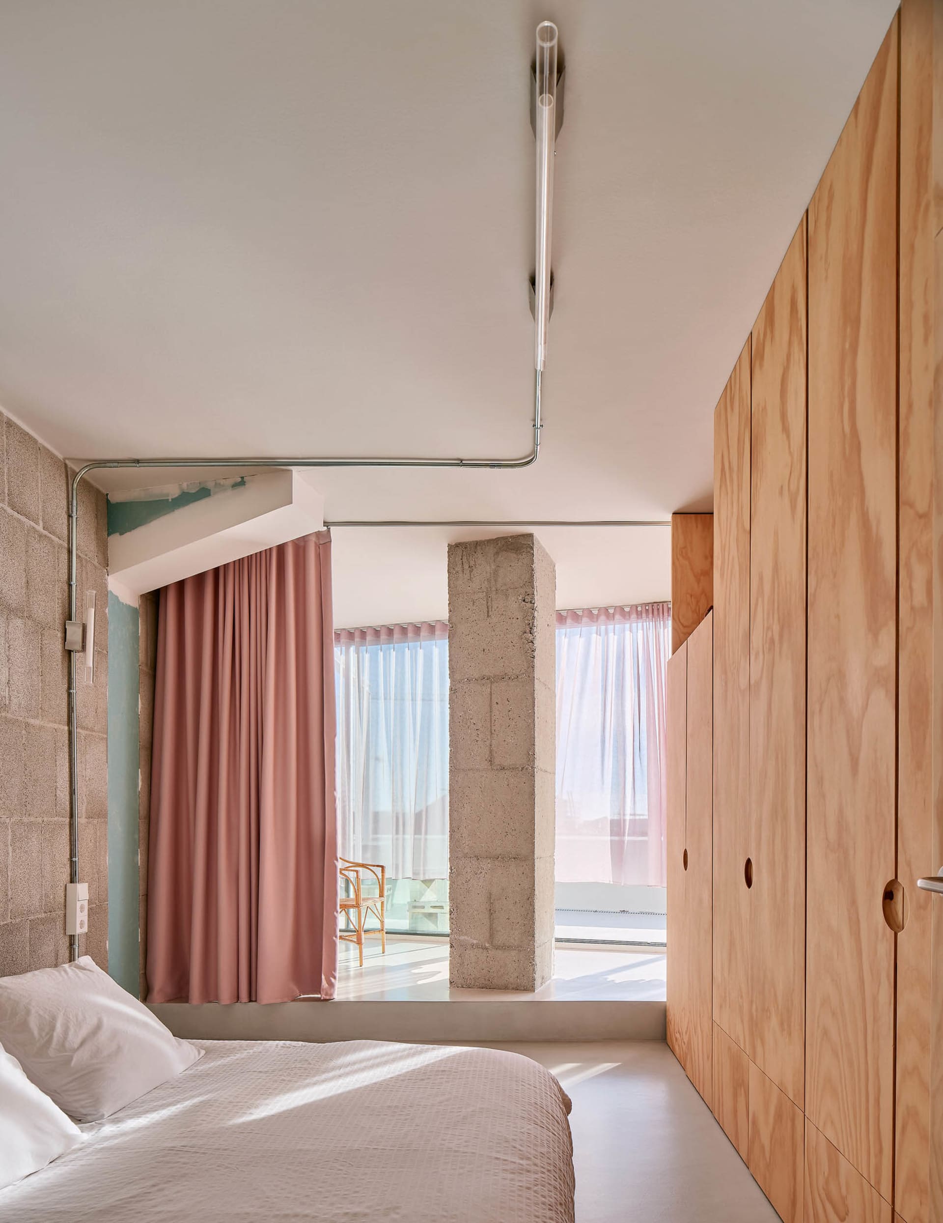 A modern bedroom featuring concrete and wooden elements.