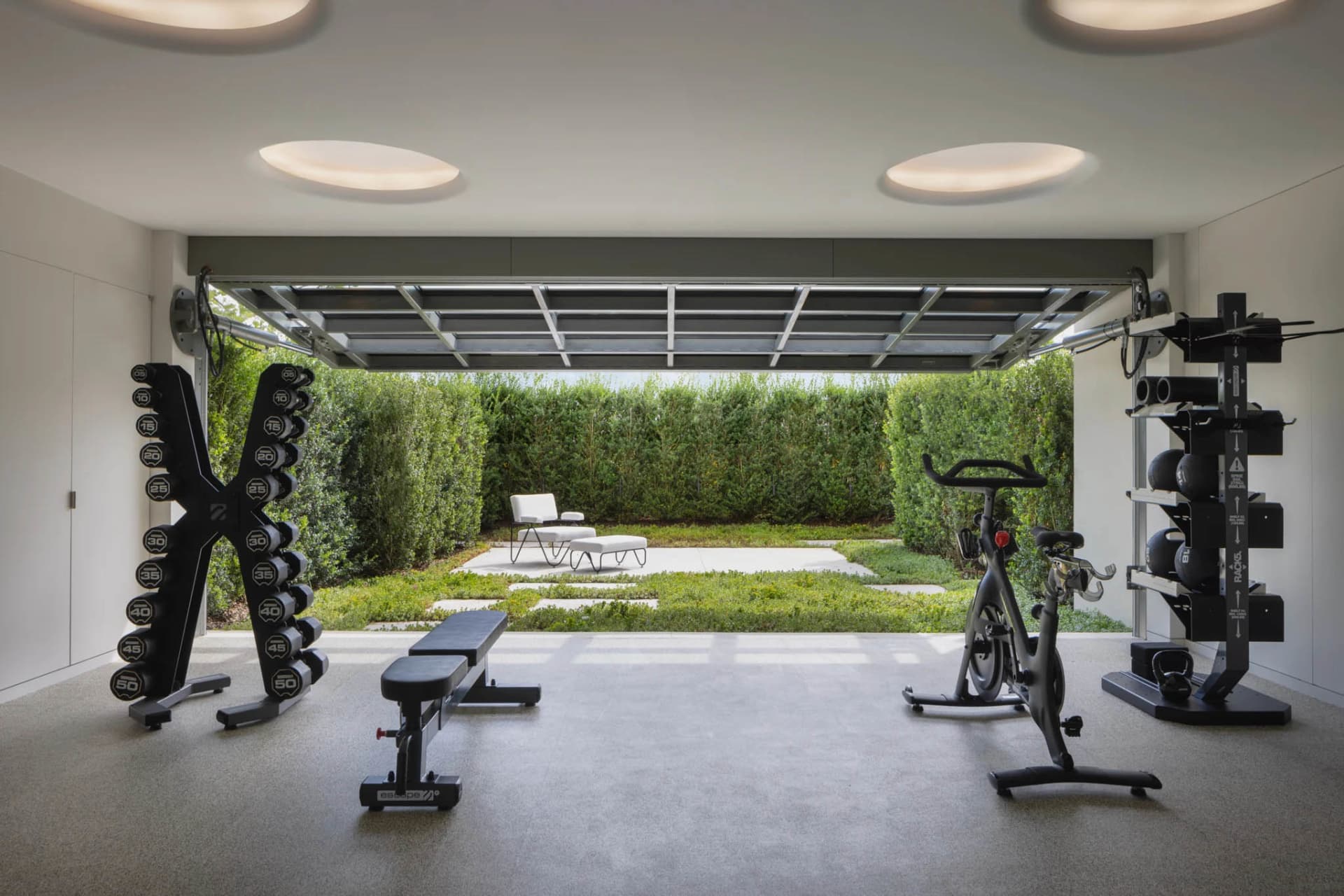 A modern home gym with concrete flooring, dumbbells, and an exercise bike.