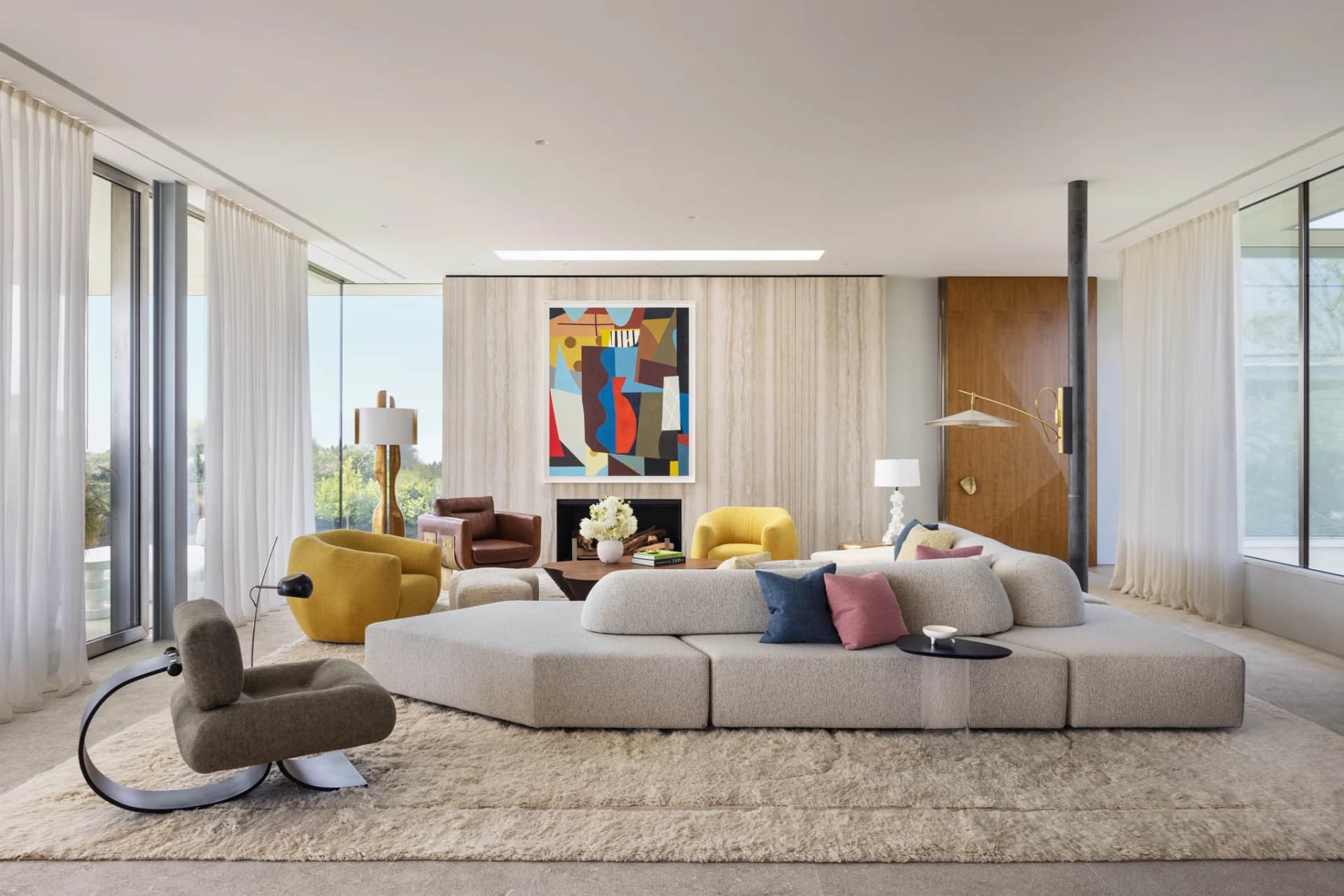 A modern living room featuring a fabric sofa, yellow armchairs, and a geometric abstract painting.
