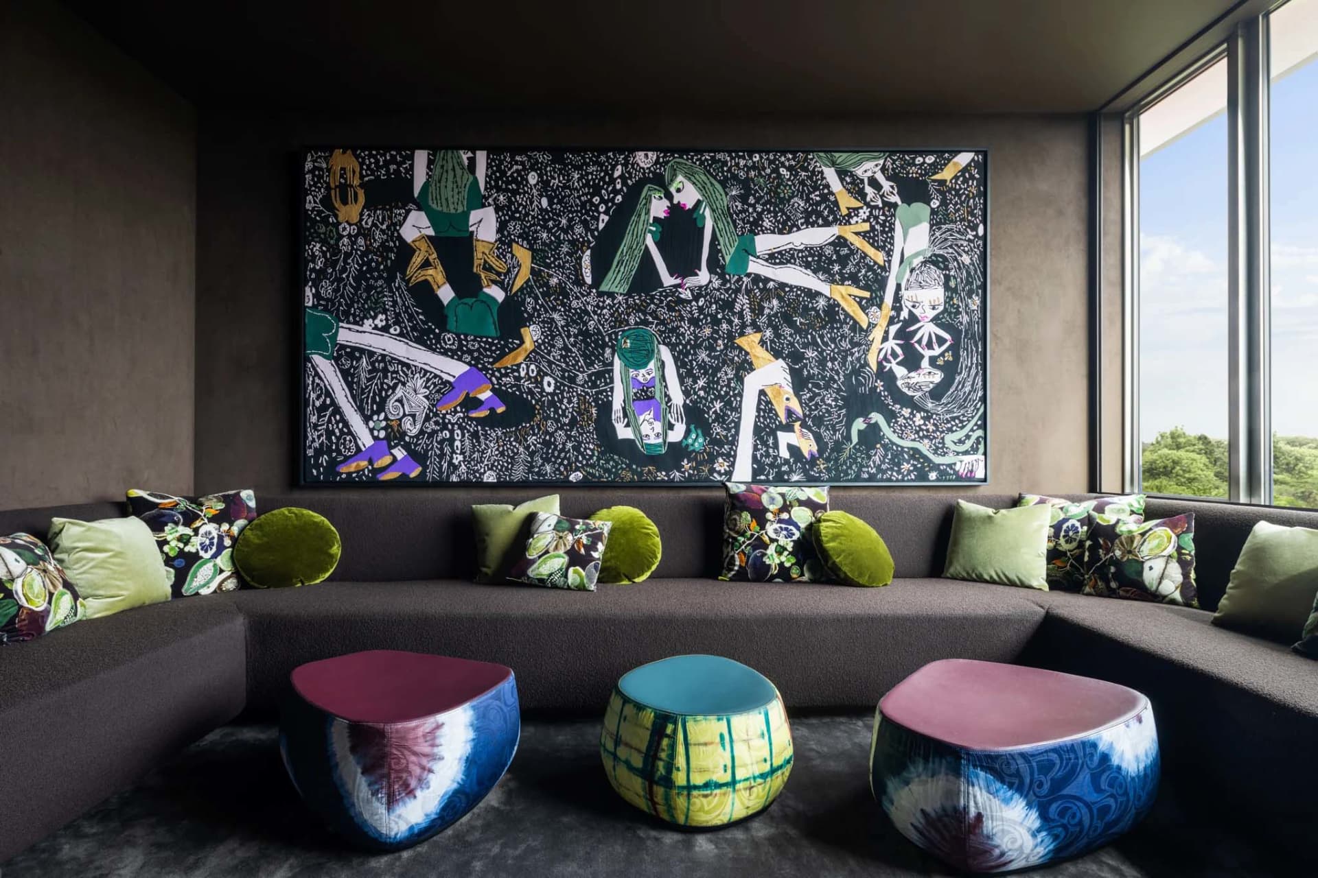 A modern lounge area featuring a large, colorful painting of figures, surrounded by a comfortable seating arrangement with pa