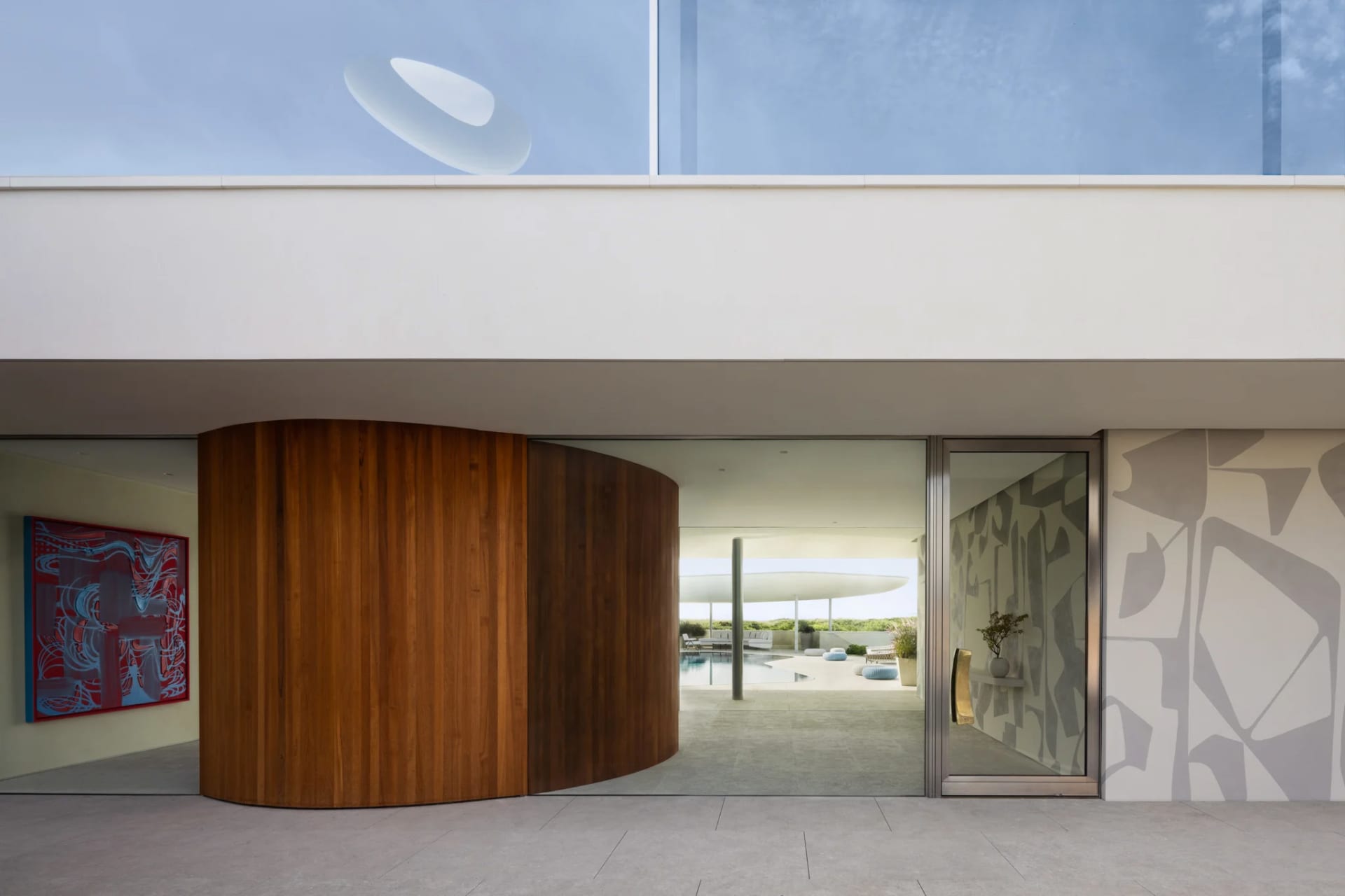 A modern residential exterior featuring large wooden columns and glass walls.