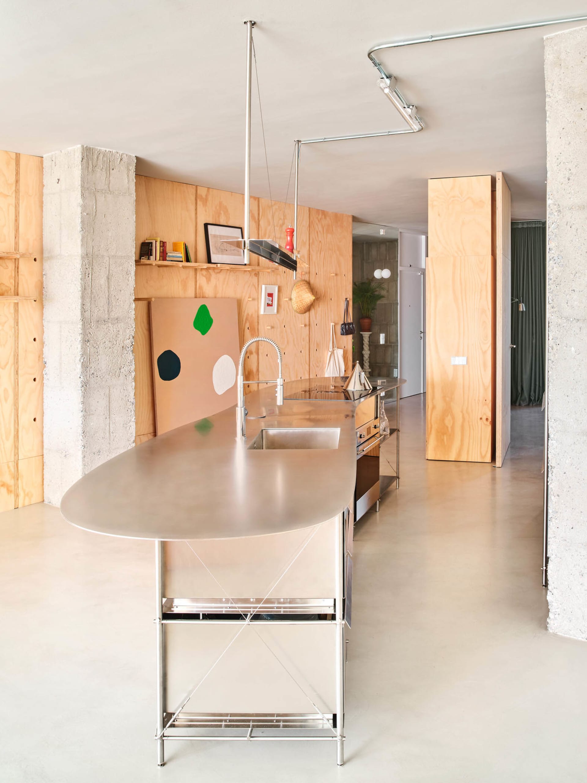 A modern minimalist kitchen with concrete walls and a stainless steel counter.