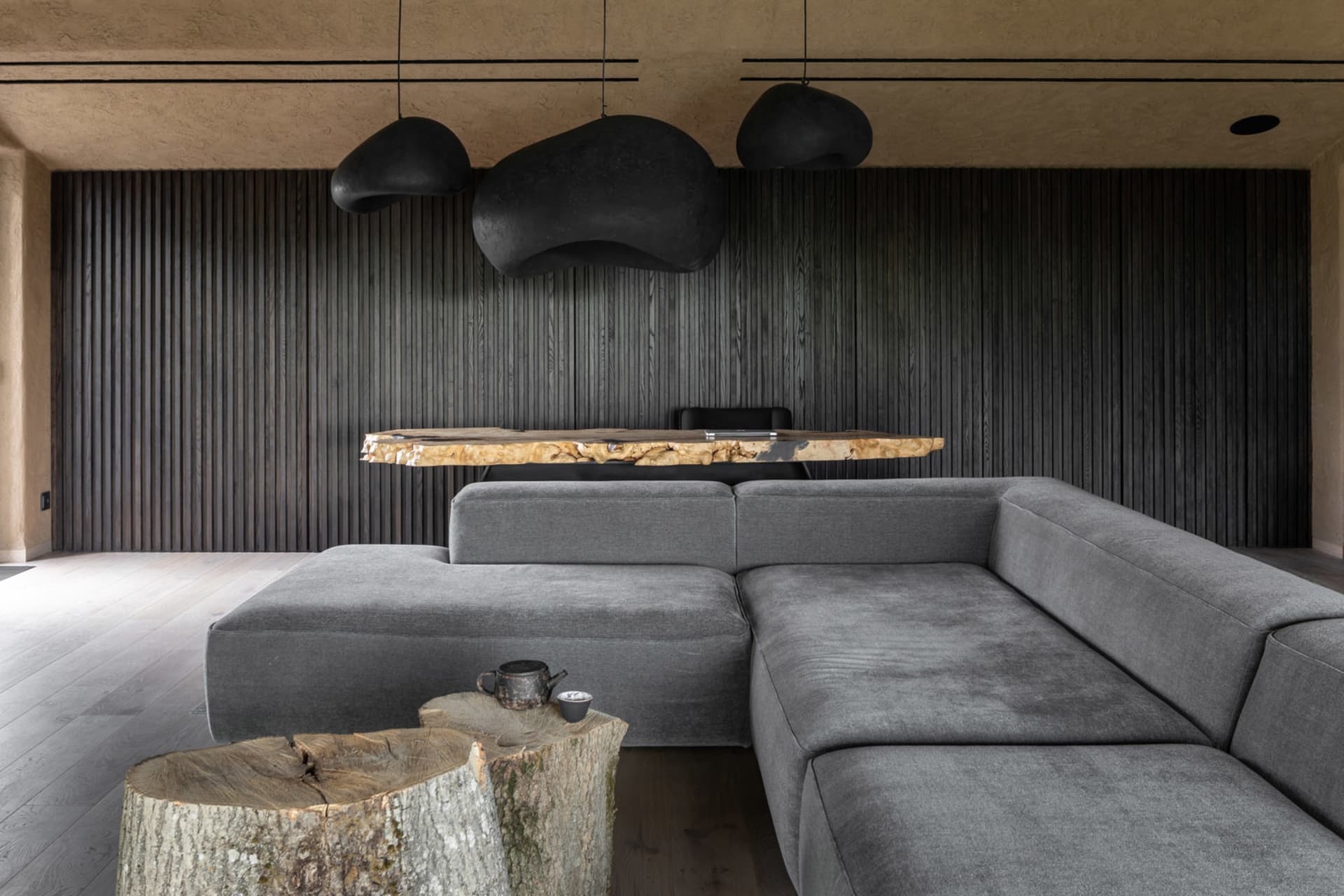 Industrial-style living room featuring wooden slat walls, a sectional sofa, and a rustic wooden coffee table with a tea set.
