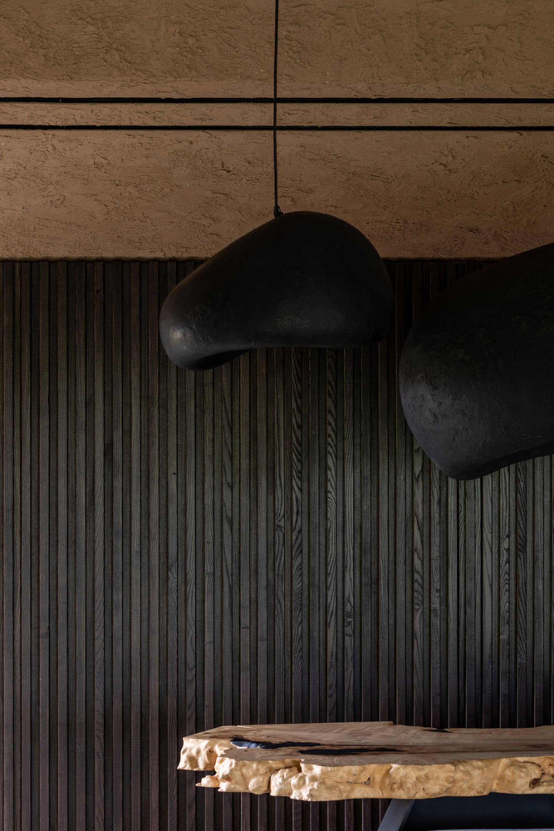 Modern, minimalist dining room with natural wood finishes and minimalistic black pendant lights.