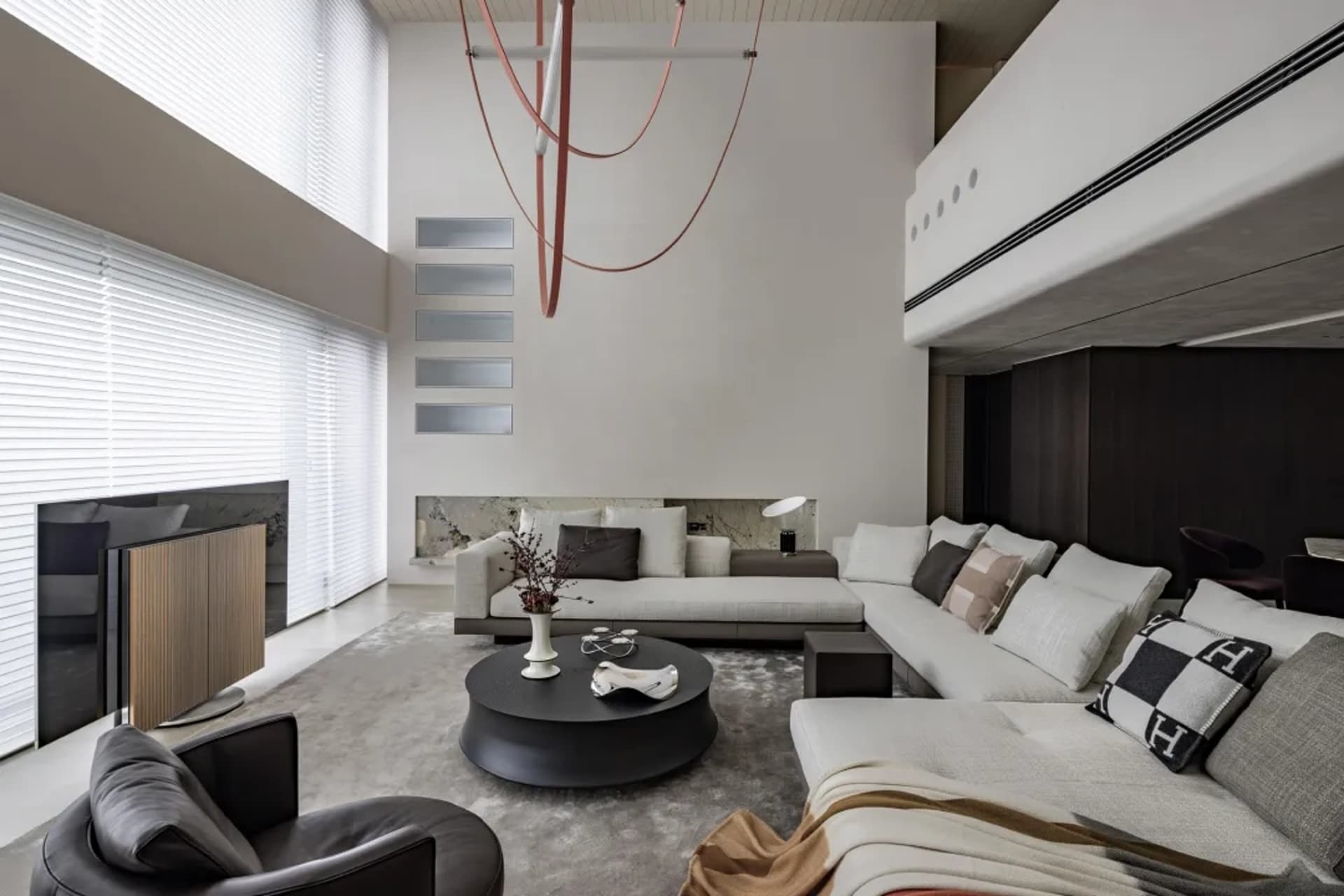 A modern living room with a white sectional sofa, round black coffee table, and large windows.