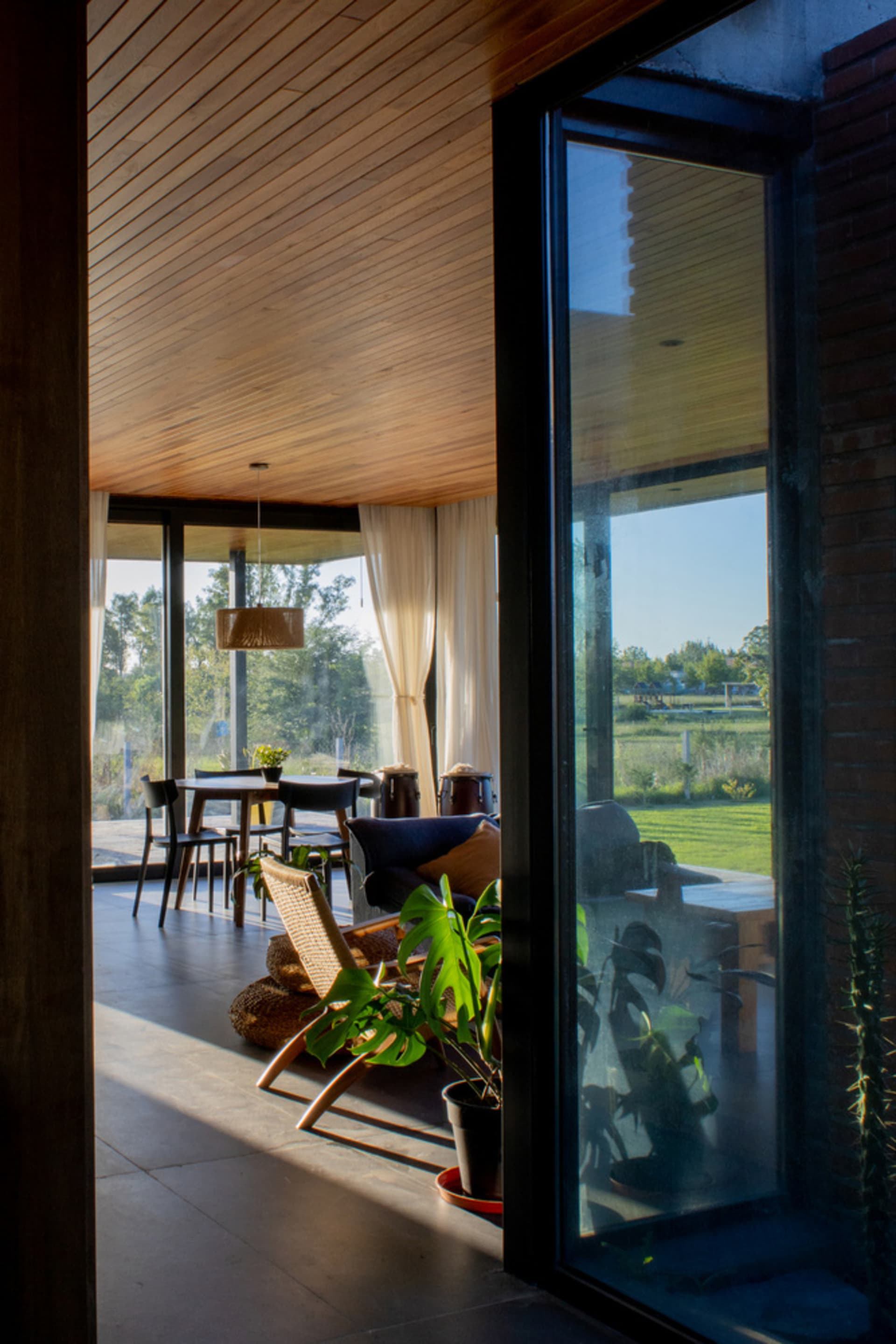 A minimalist living room with wooden flooring, glass sliding doors, and a comfortable seating area.