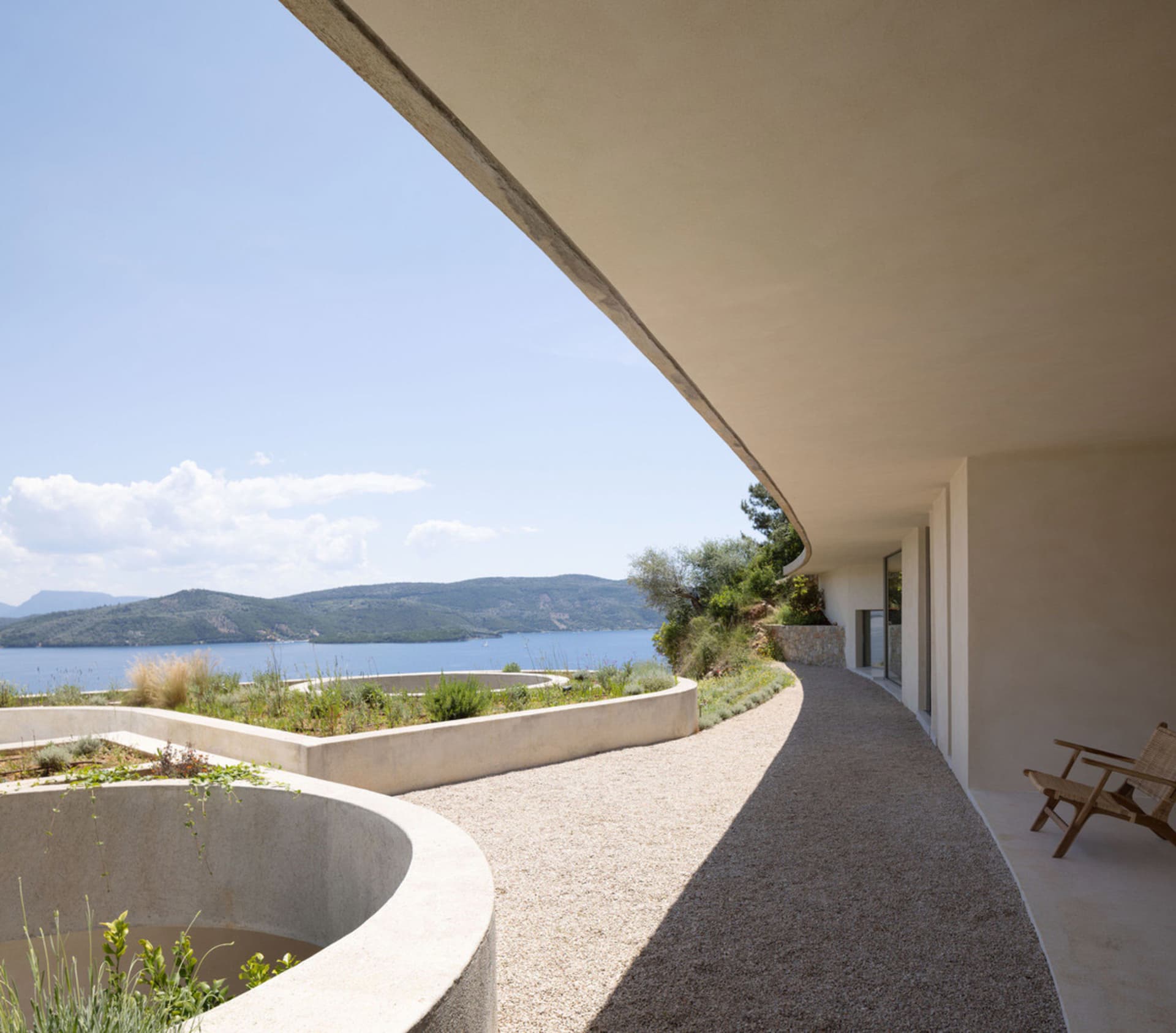 Modern house with a concrete patio overlooking the sea.