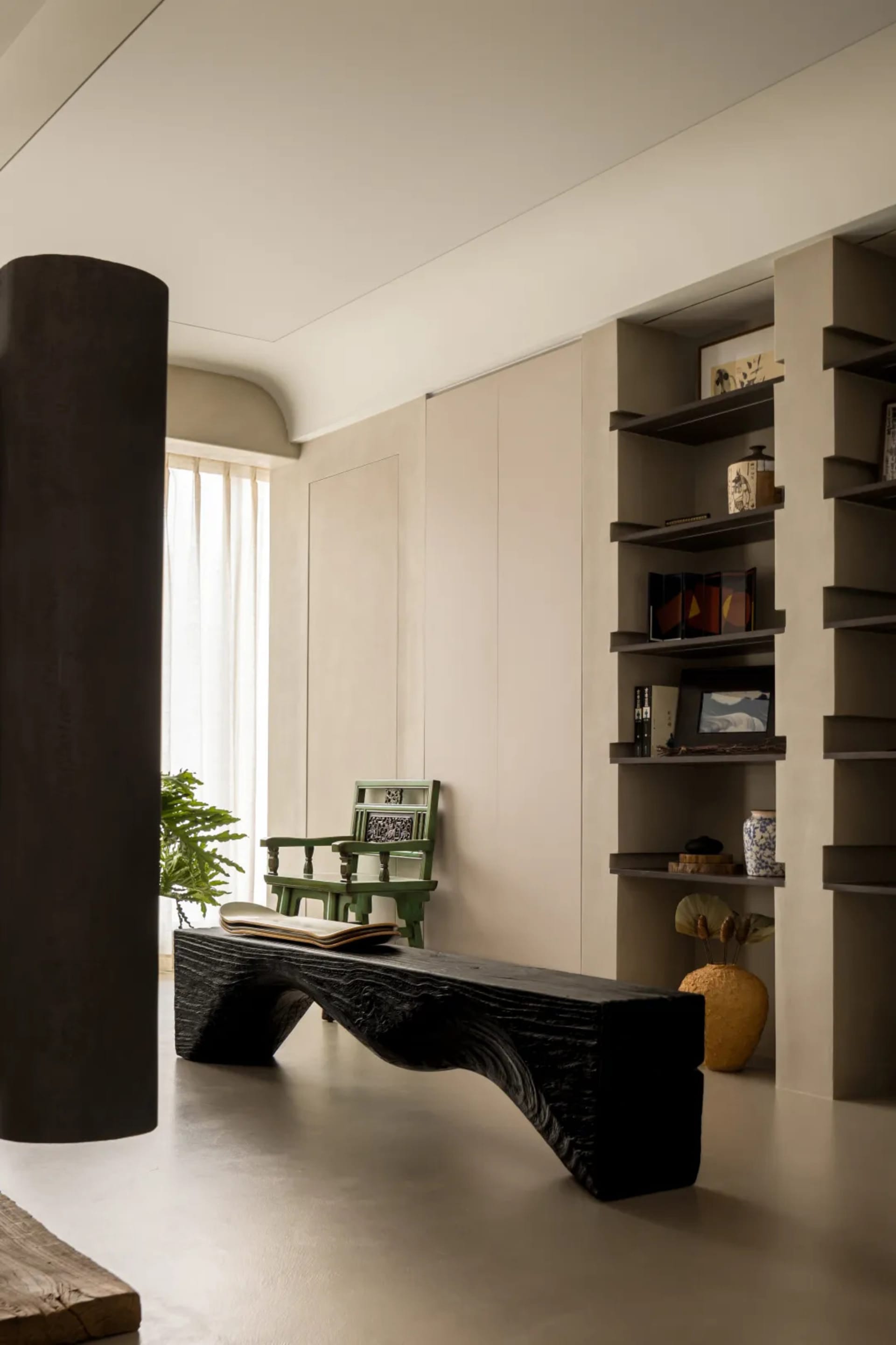 Modern minimalist living room with concrete floors, a sleek black coffee table, and a green armchair.