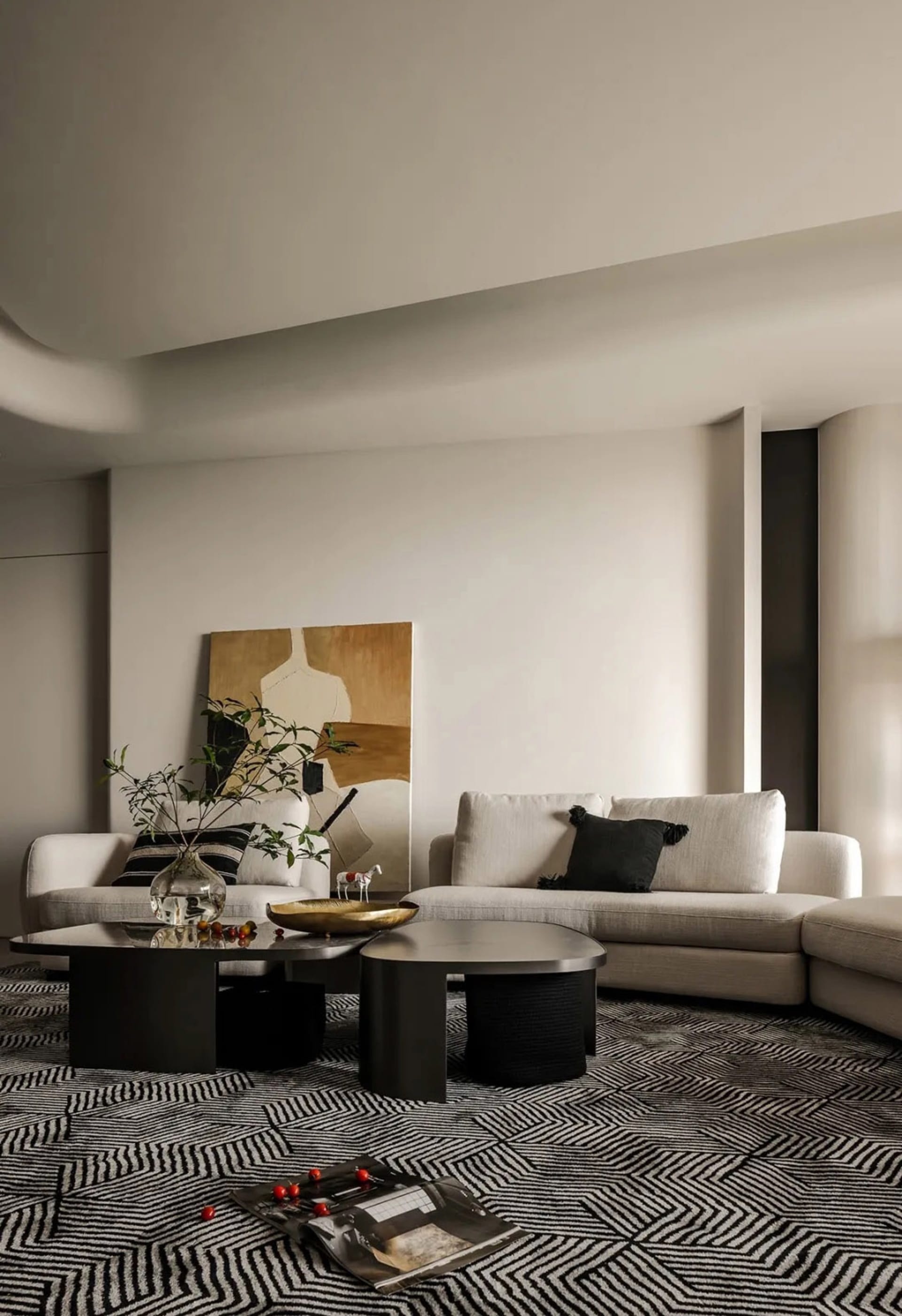 Modern living room with beige sectional sofa, patterned rug, and abstract art