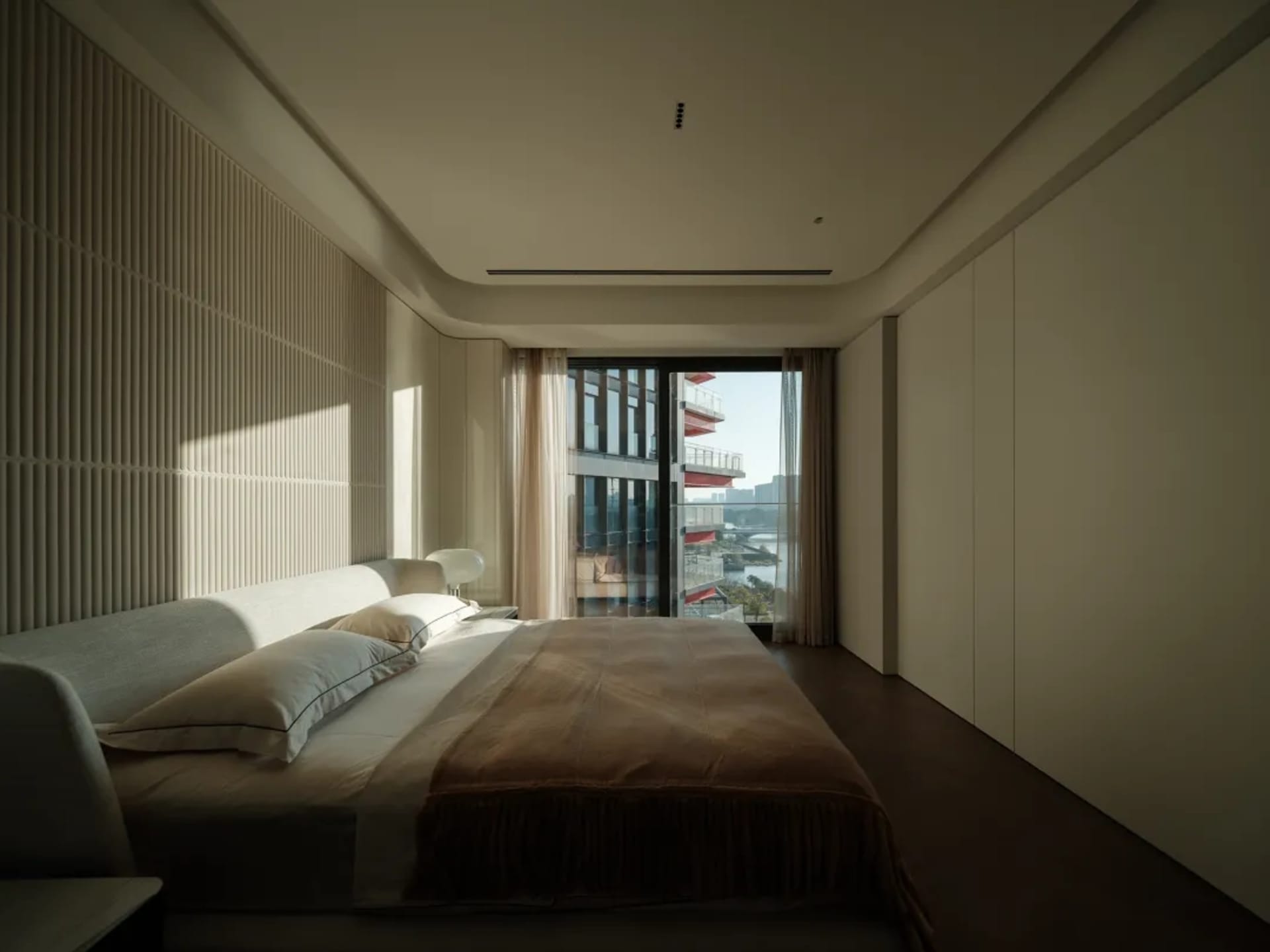 Modern minimalist bedroom featuring a bed with wooden frame, glass window, and fabric bedding.