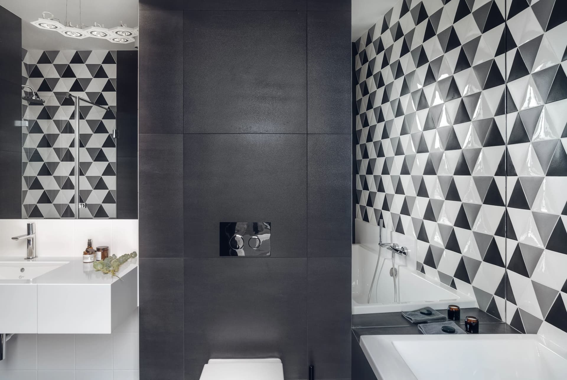 A modern bathroom featuring a black and white patterned tile wall, a walk-in shower, a white bathtub, and a floating white va
