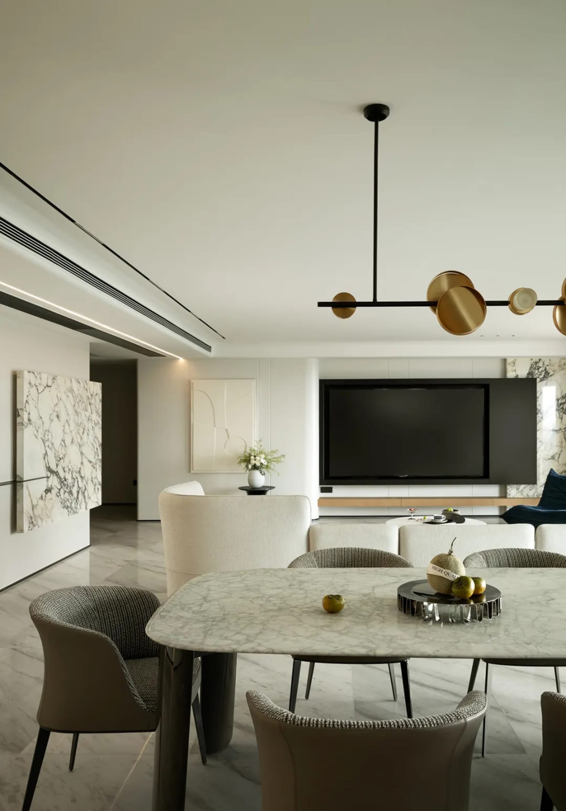 A minimalist living and dining room with marble accents and modern furniture.