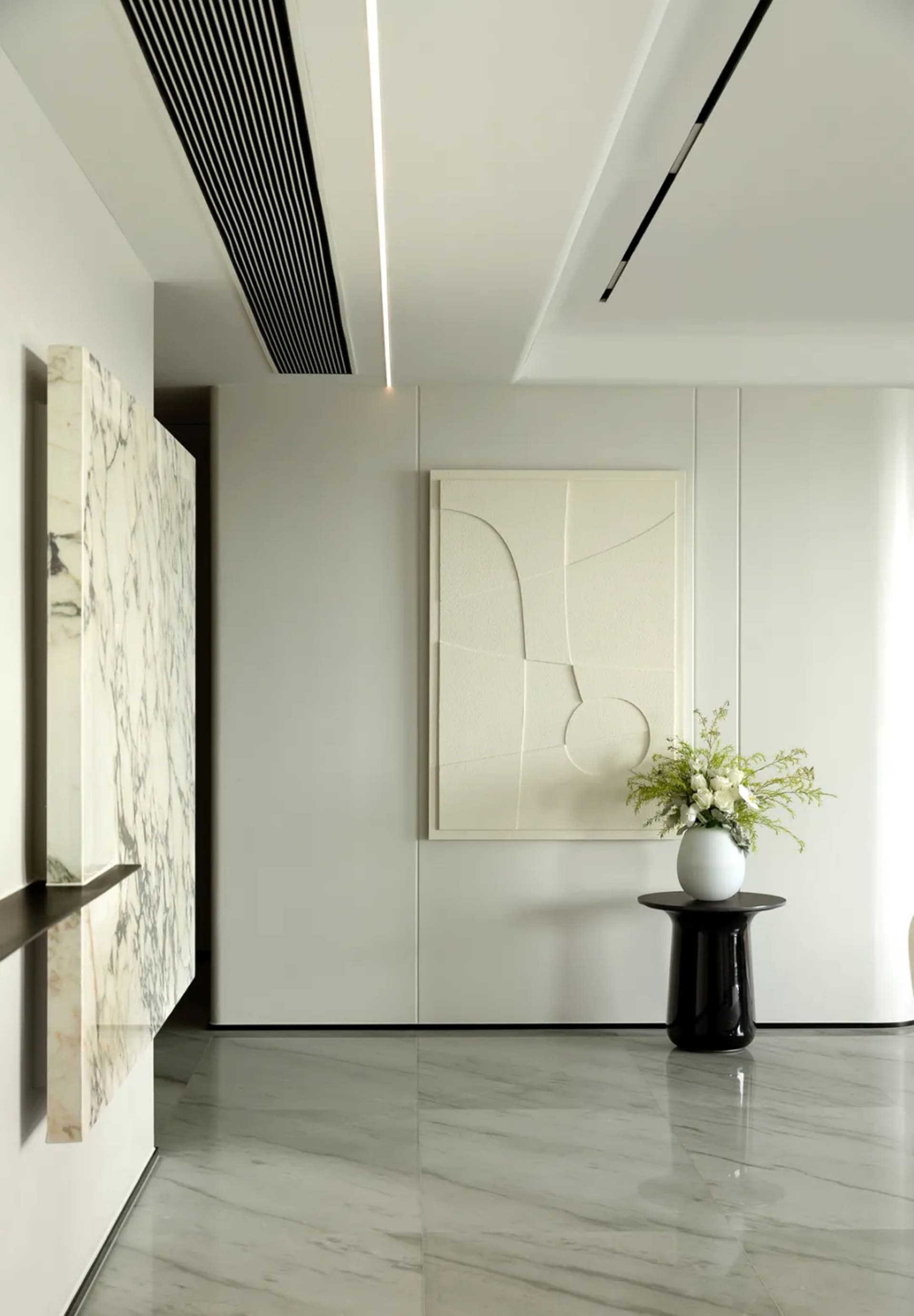 Modern interior design featuring a minimalist entryway with marble flooring and white framed art.