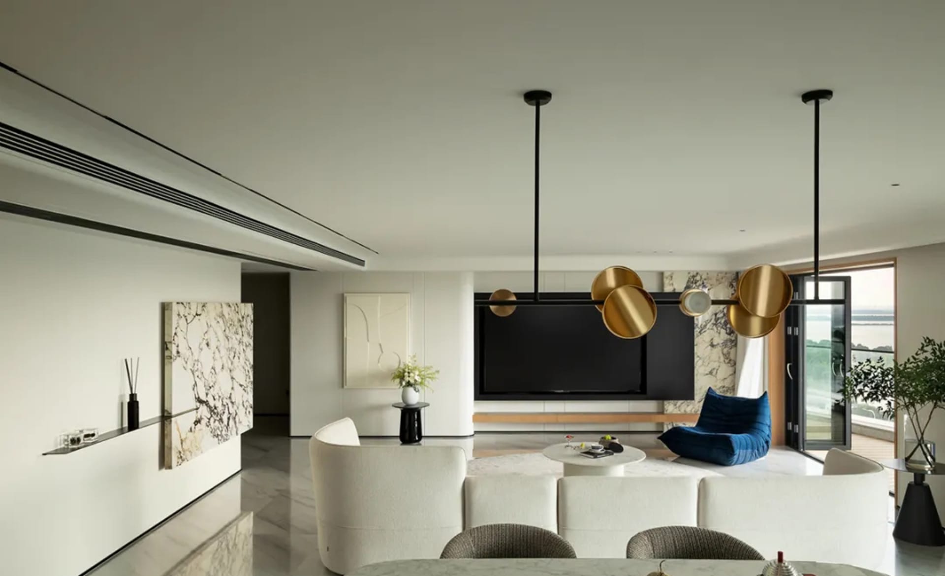Modern living room featuring a stylish, minimalist design with a marble accent wall, a cozy blue lounge chair, and a round ma