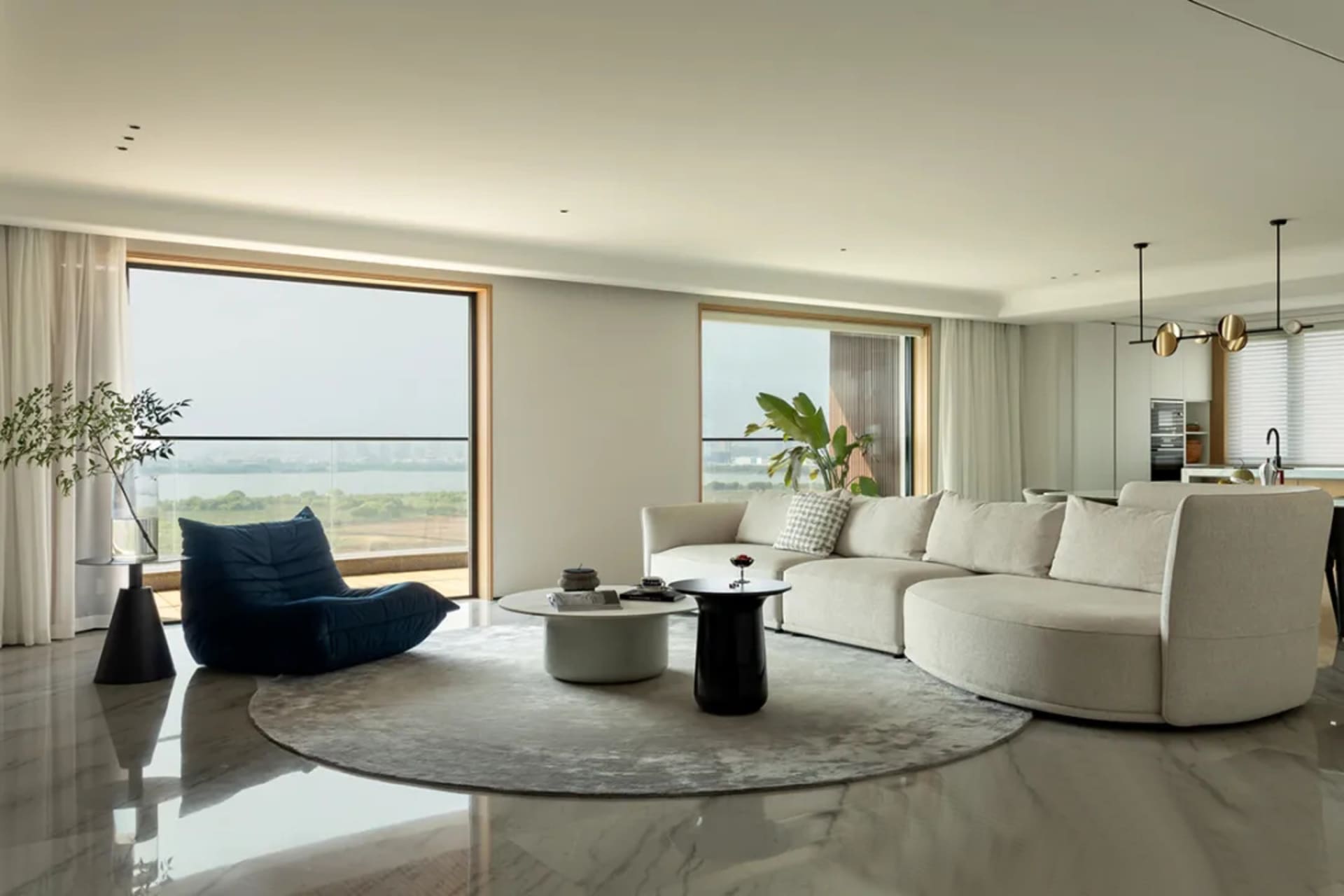 Modern living room featuring a white sofa, round coffee table, and large windows showcasing a scenic view.
