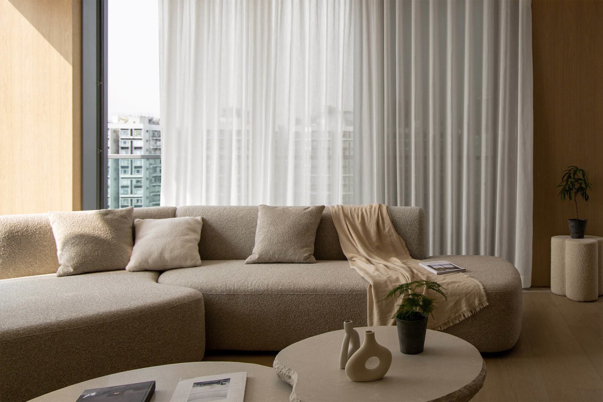 A modern, minimalist living room with a large, comfortable couch upholstered in neutral, textured fabric and accented with si