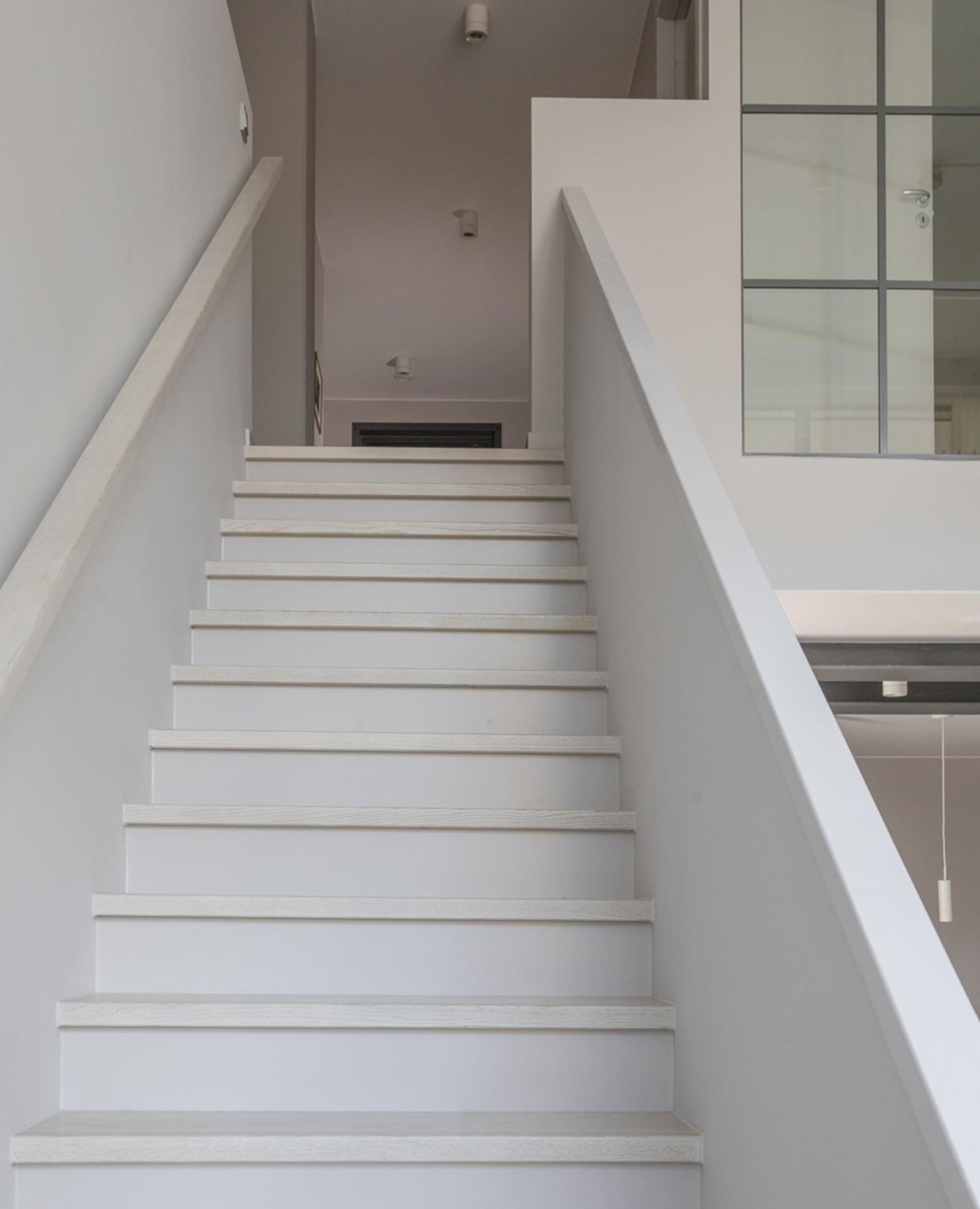 A modern minimalist staircase with white steps and railings.