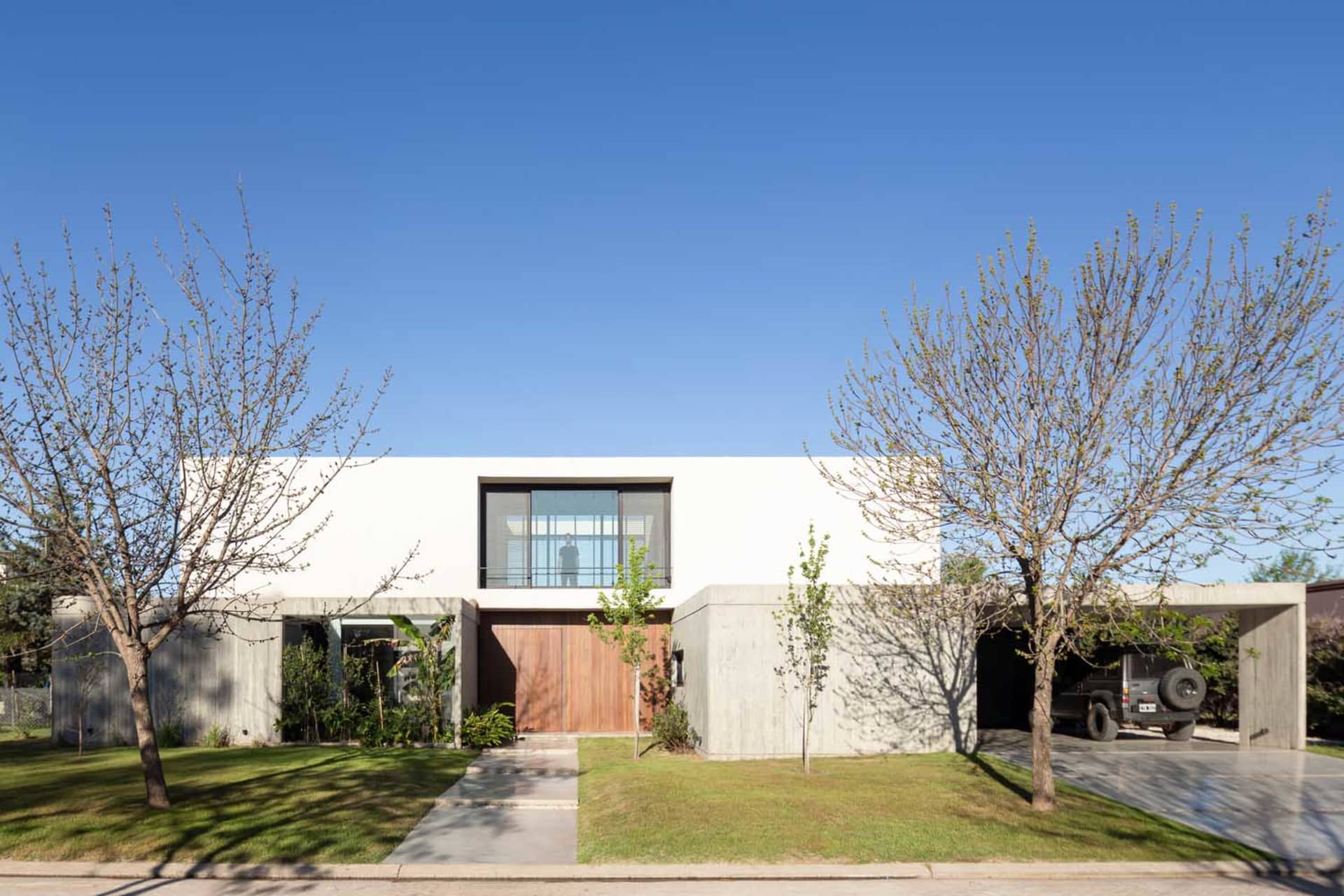 Modern residential house featuring concrete walls, glass windows, and wooden doors.